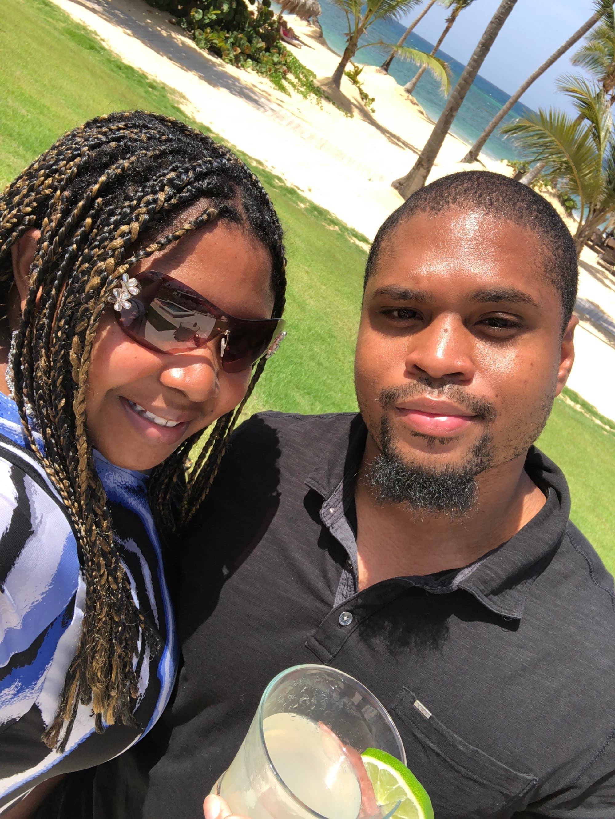 A couple posing for a selfie outside with the beach in the background.