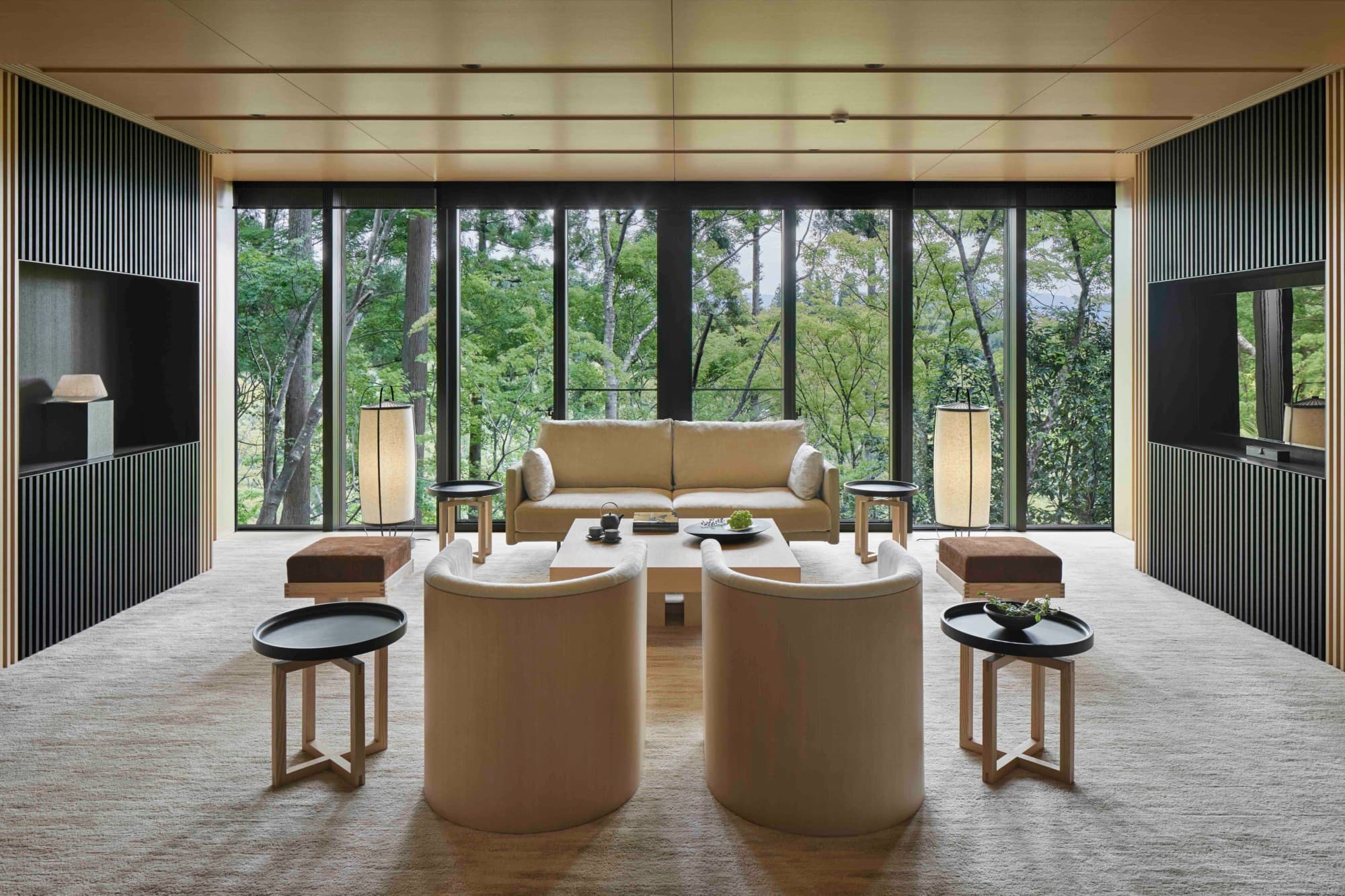 a stylishly minimalist room with floor-to-ceiling windows overlooking a forest