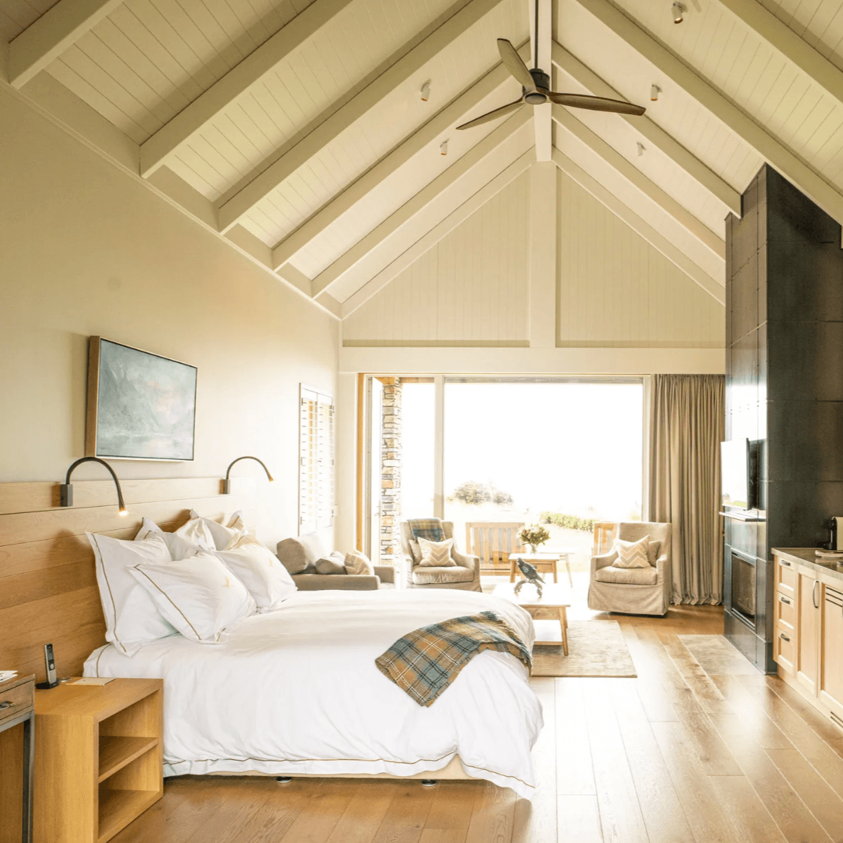 a large white bed in a sunlit bedroom with an A-shaped ceiling
