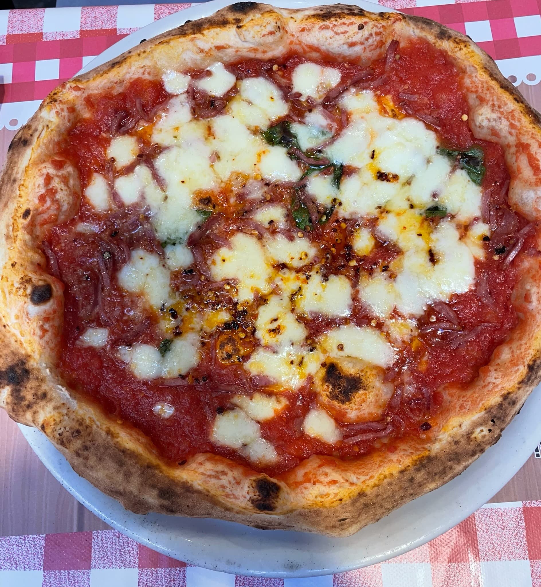 A margherita pizza on a red and white tablecloth.