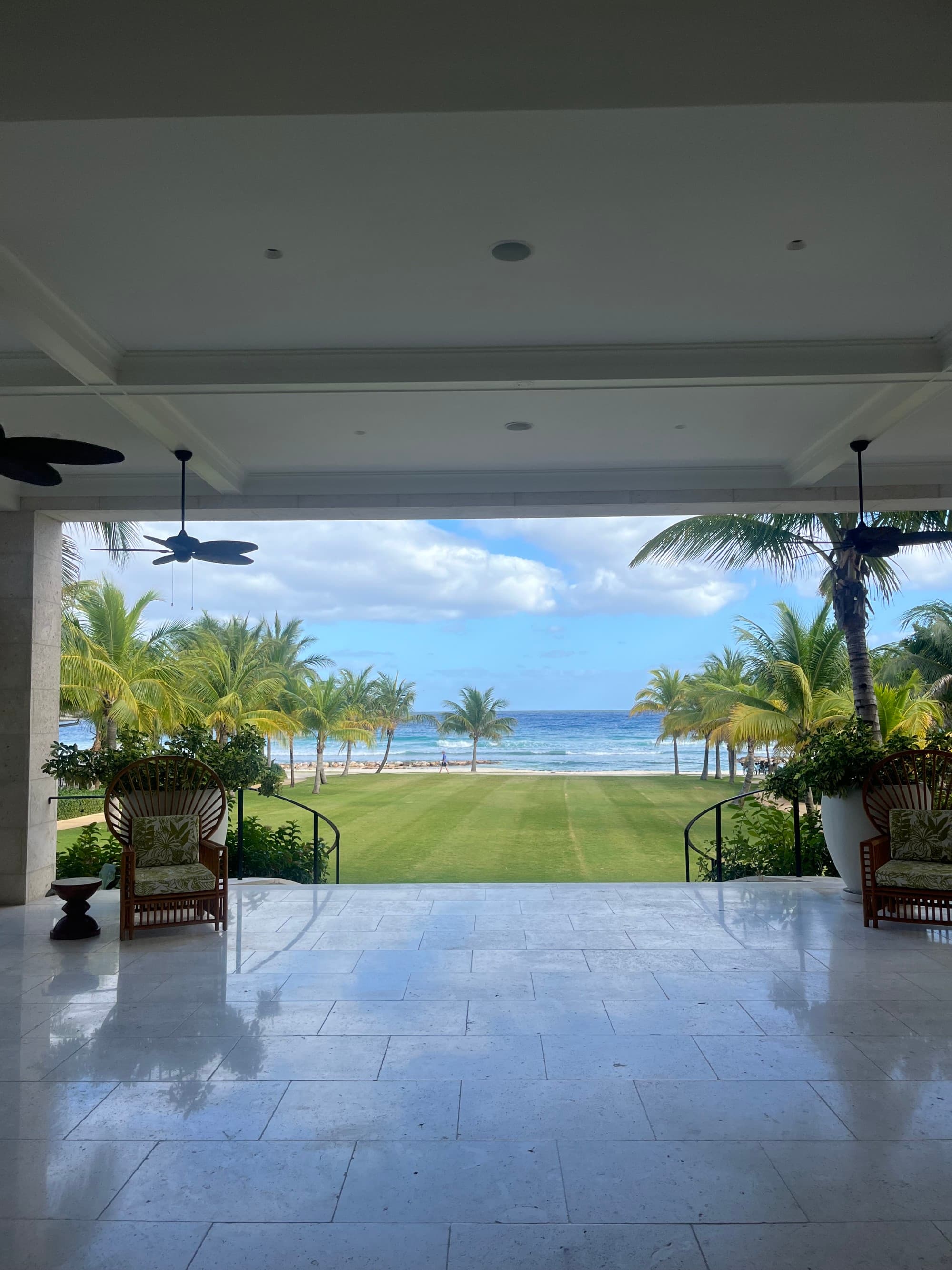 The open-air hotel lobby overlooking the lawn with the ocean in the distance.