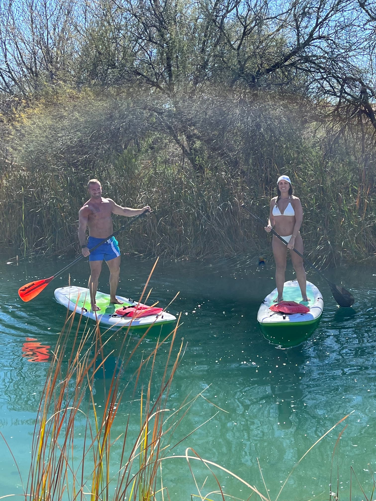 Travel advisor Kelly paddleboarding in a white bikini on a river with a male companion