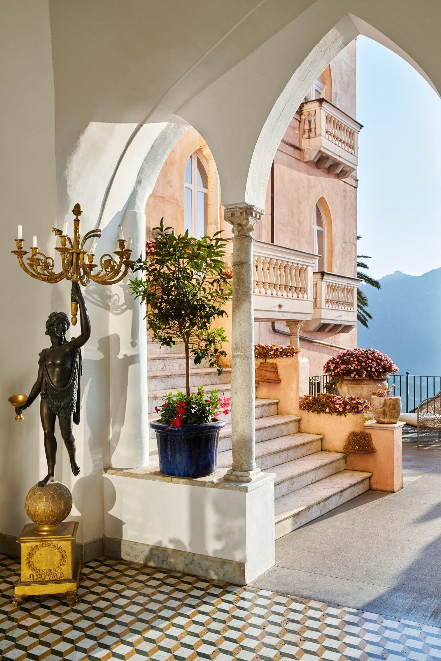 a statue holds a bronze light fixture on an elegant seaside terrace