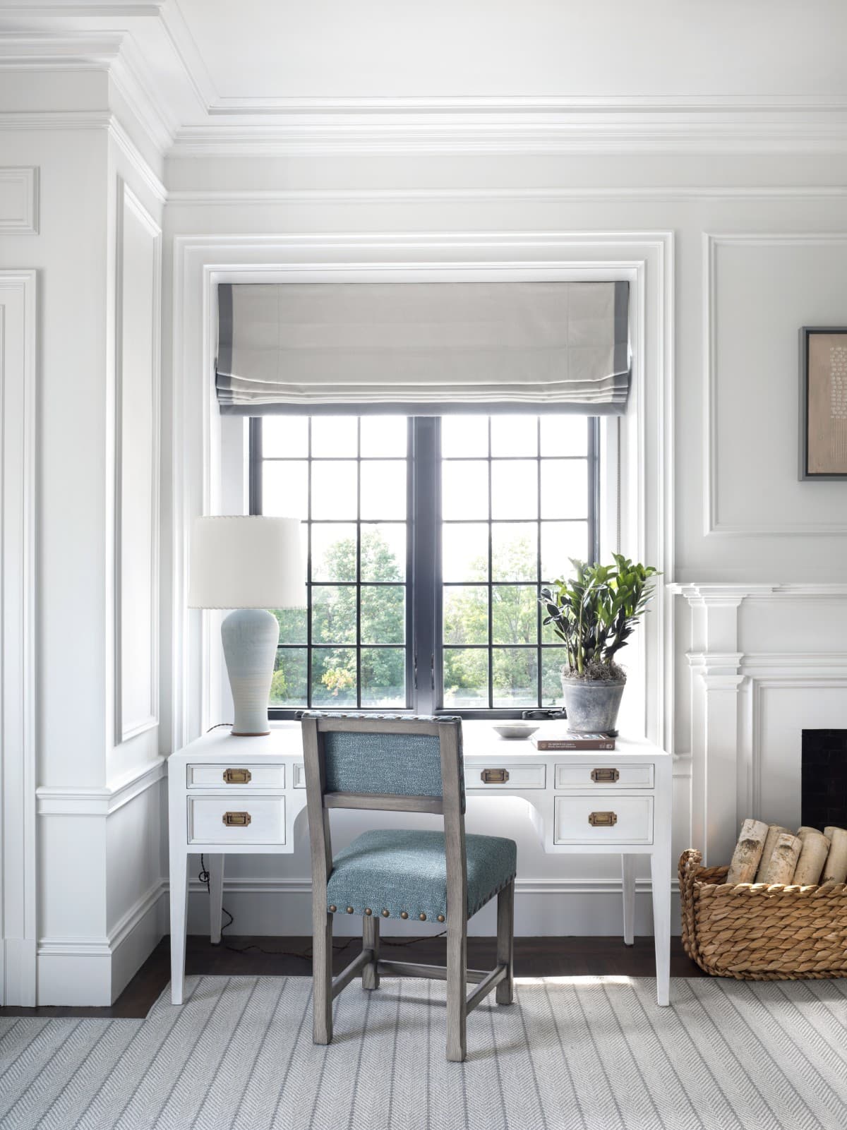 a blue chair sits in front of a white desk in front of a large window