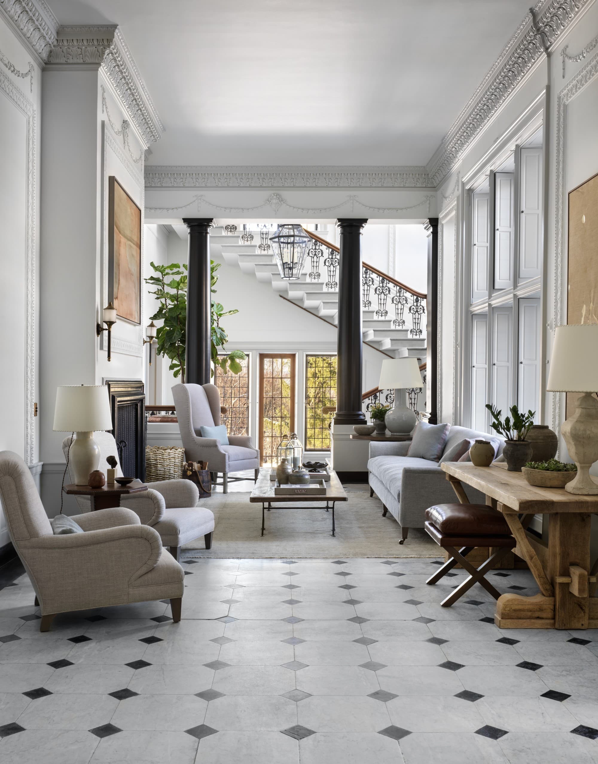 a grand foyer with white tile and a white-staired staircase