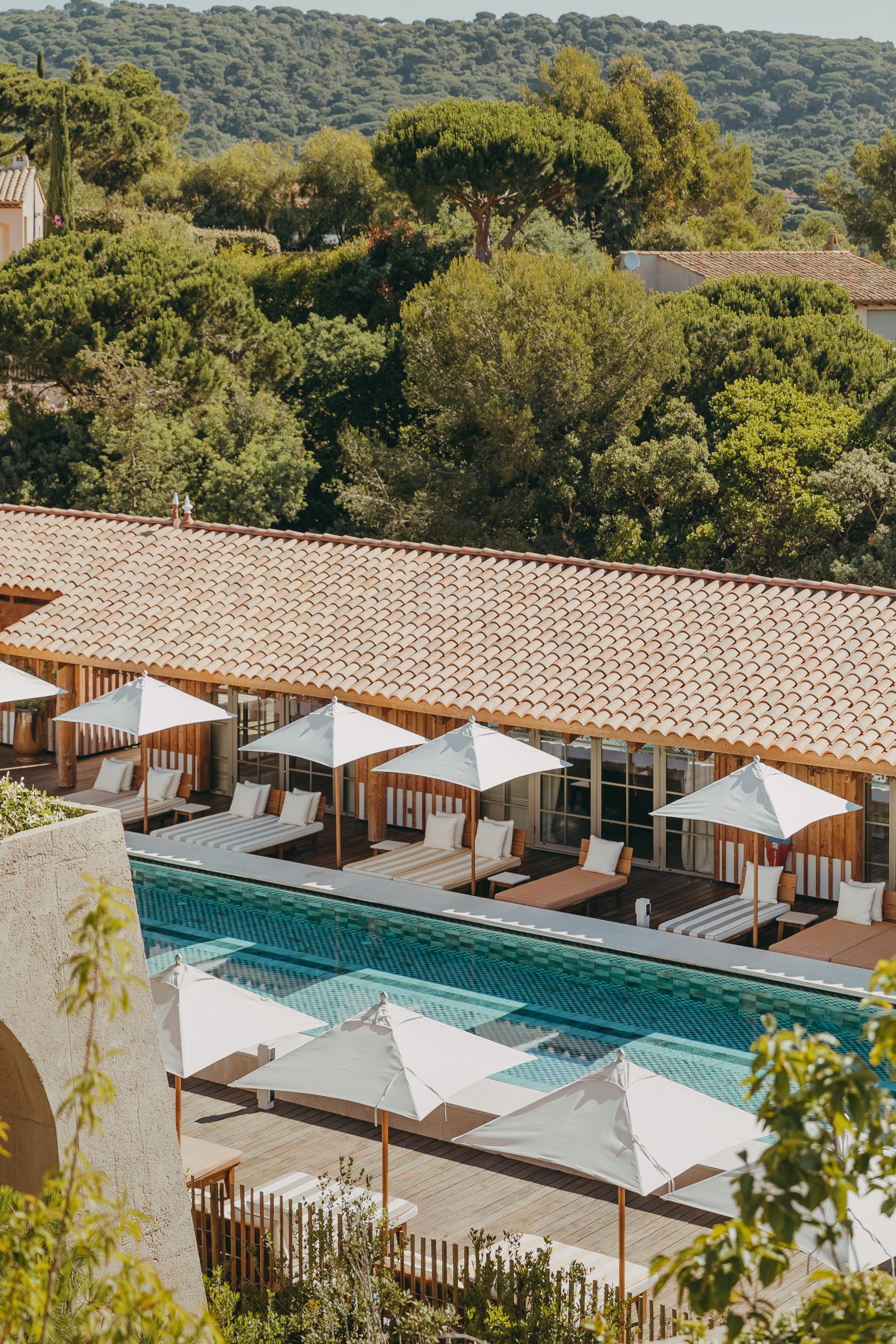 aerial view of a pool surrounded by white umbrellas in a lush landscape