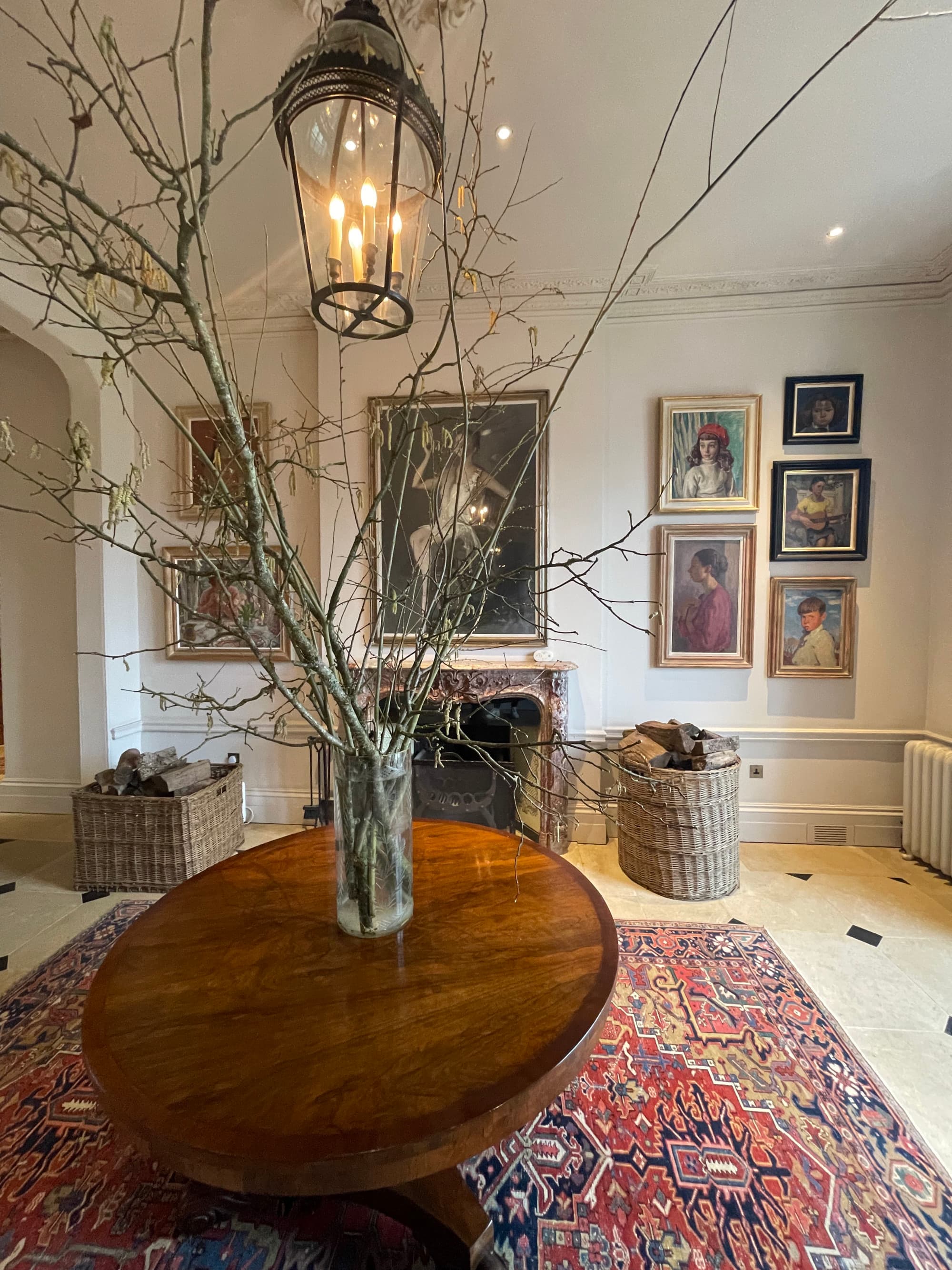 An entryway with a wooden table topped with a vase and paintings on the walls