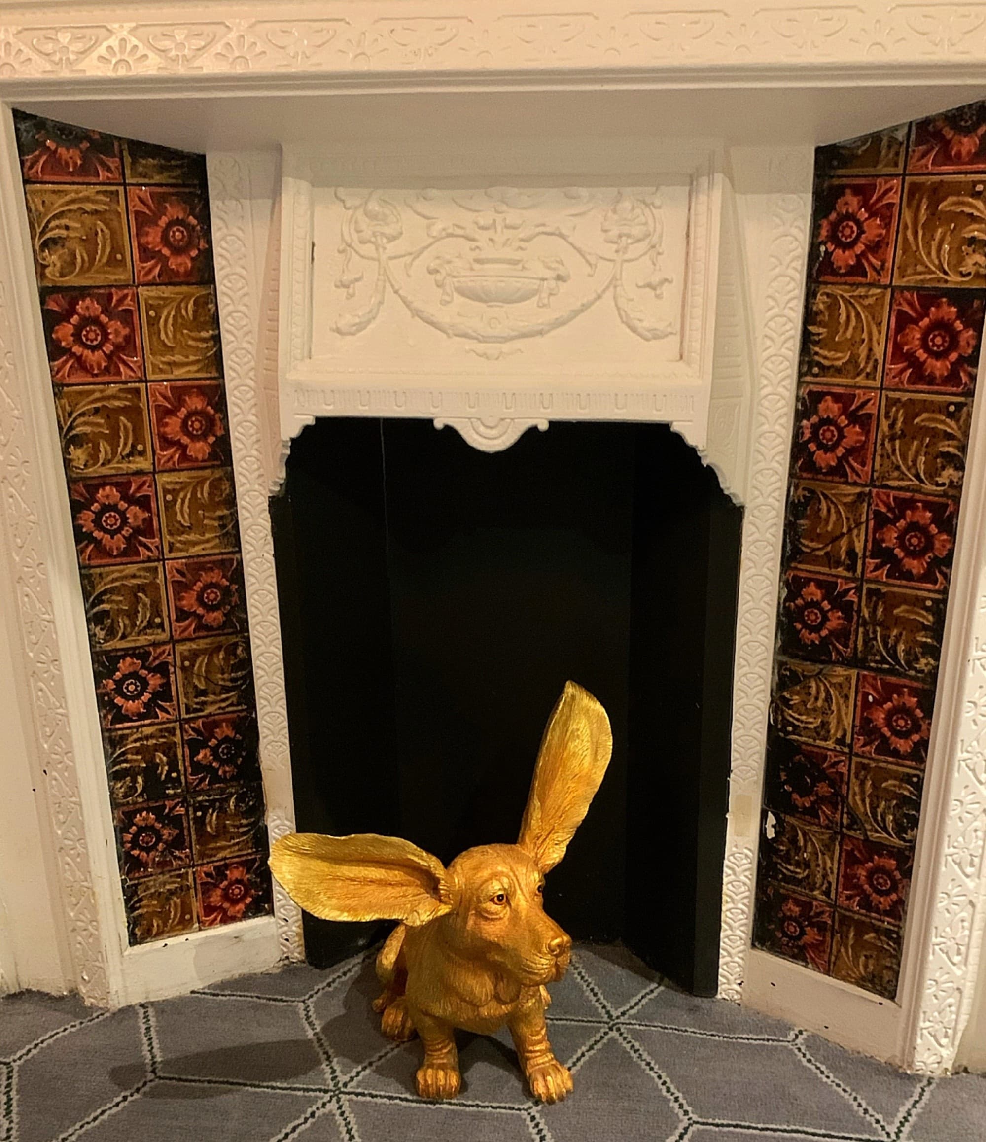 A brass statue of a dog in front of a fireplace