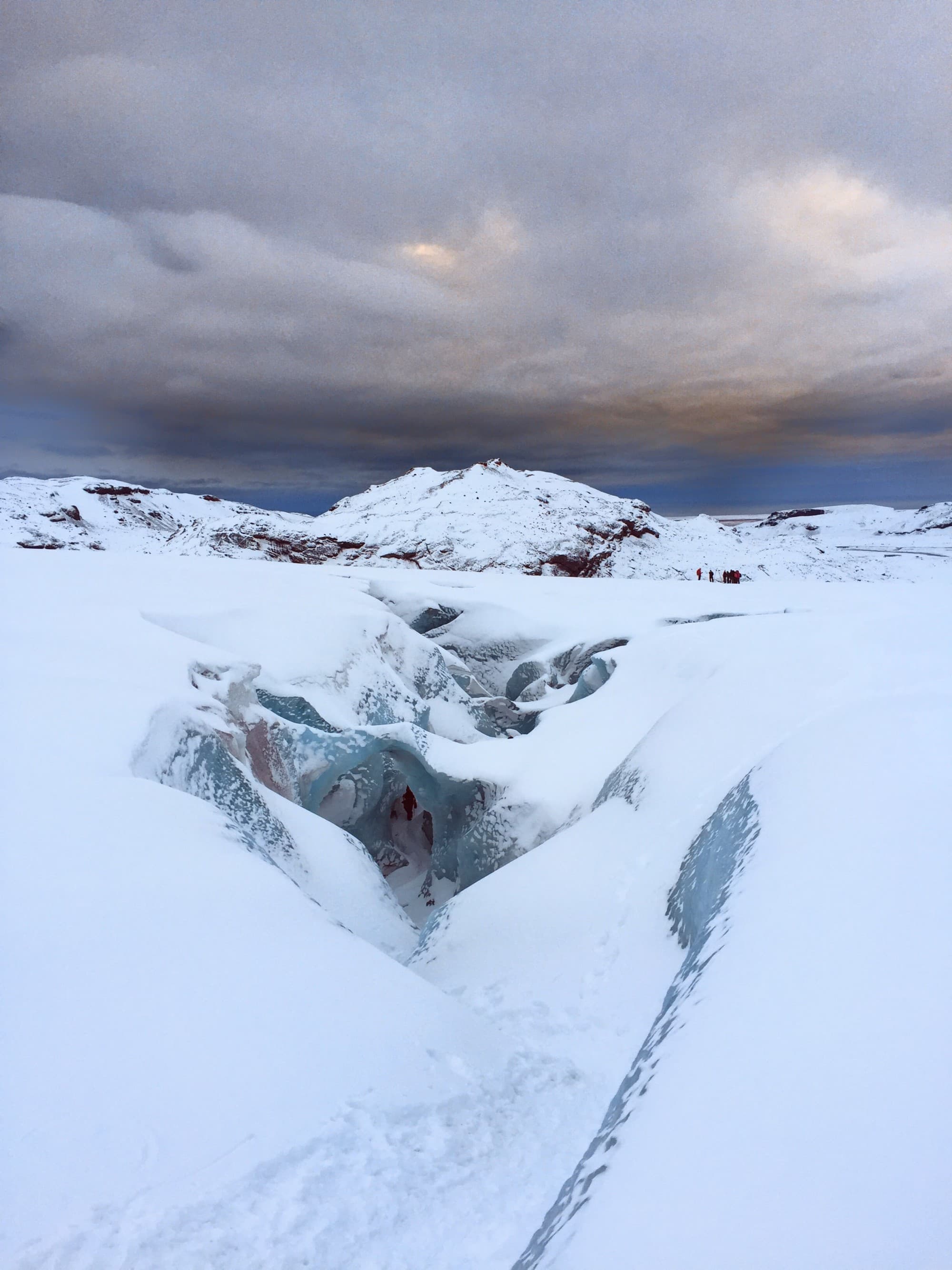A view of a glacier whilst on a hike with the sun subtly peaking through the thick clouds in the distance.
