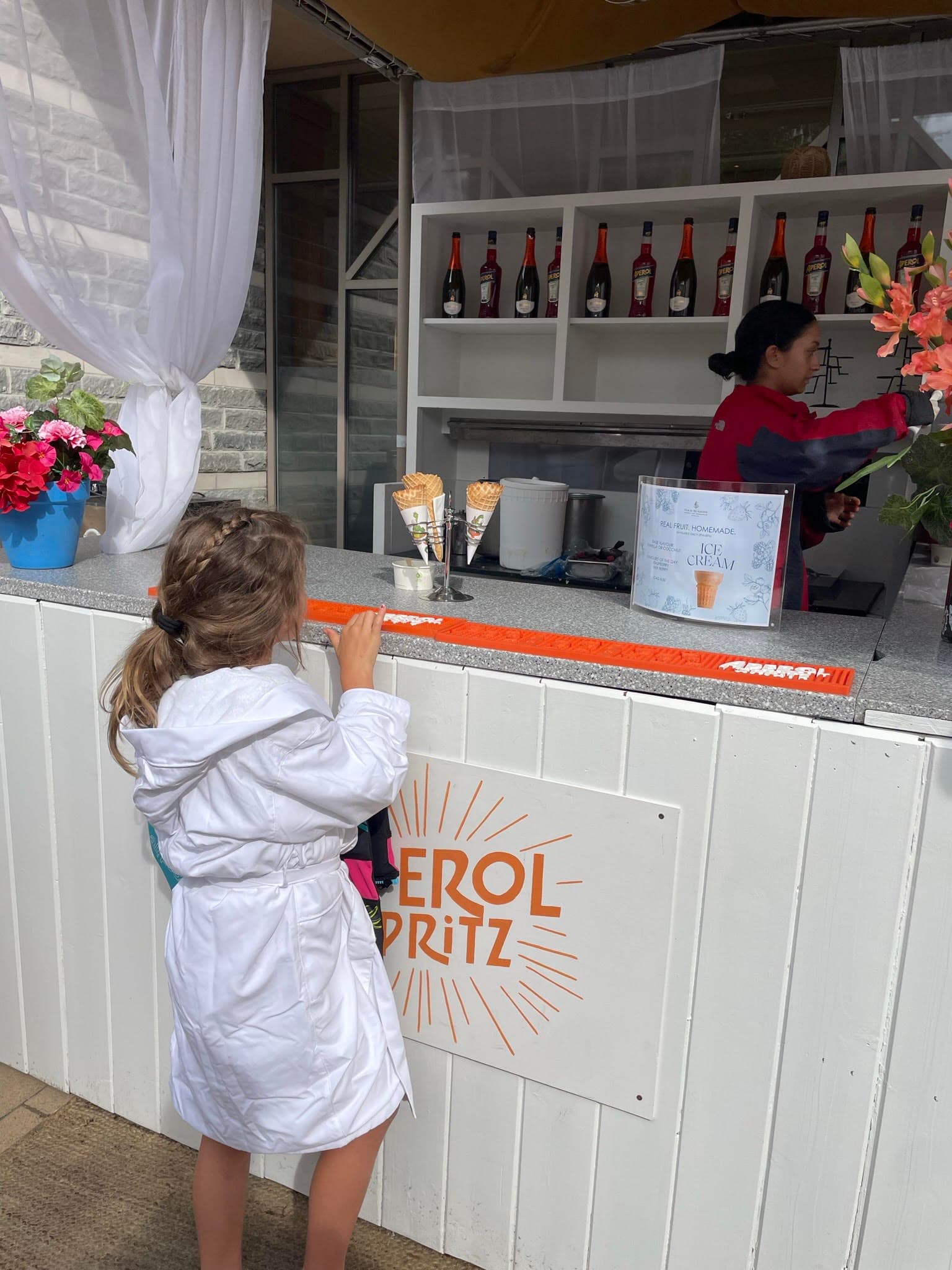 A small child at a counter getting snacks in a white robe.