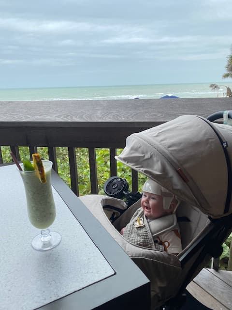 A baby sitting in a stroller at an indoor restaurant