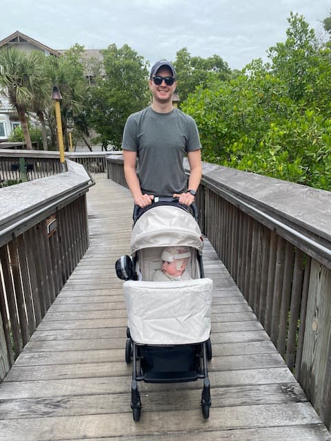 A person pushing a stroller with a baby on a wooden boardwalk