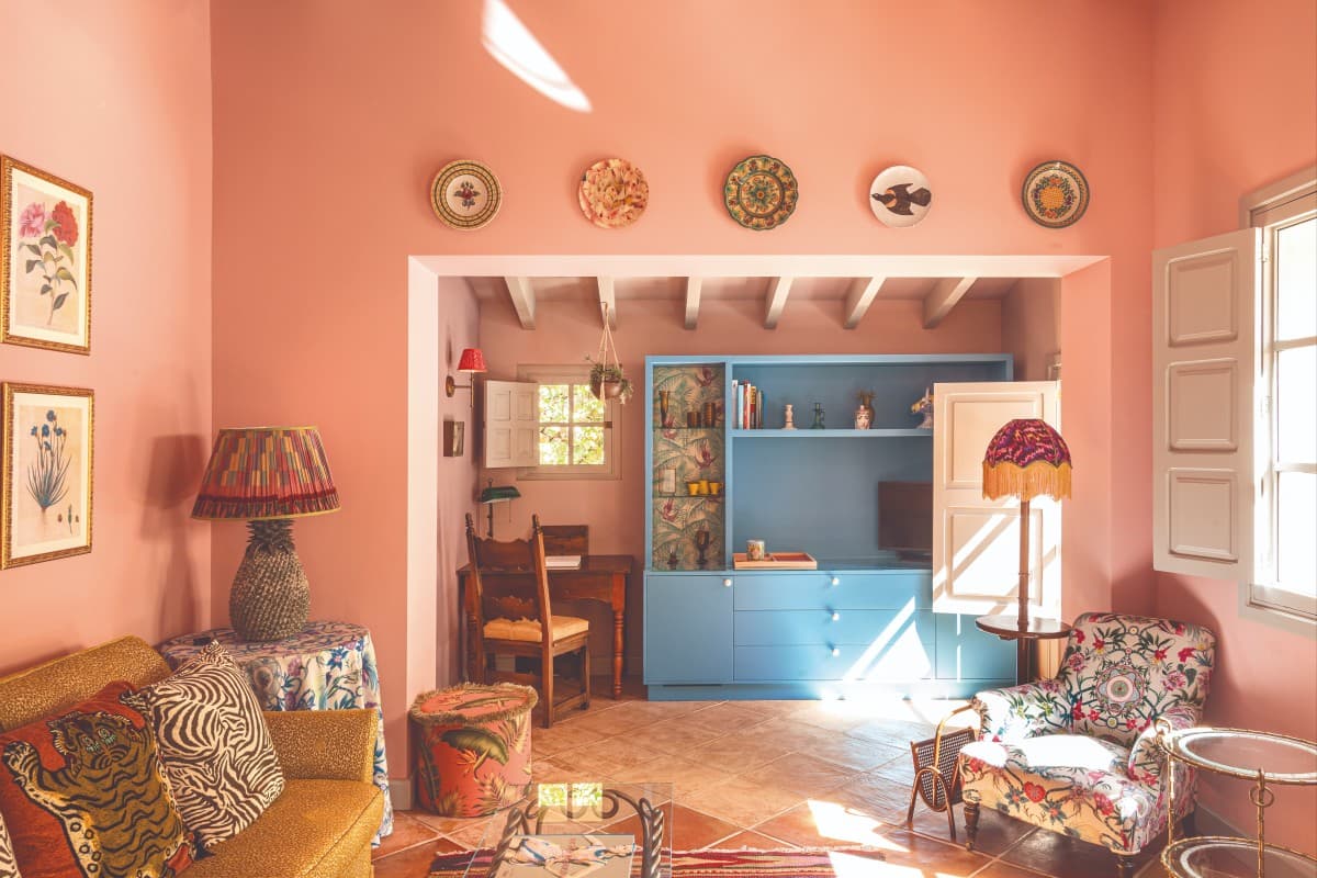 a seating area with pink walls and furniture covered in floral prints