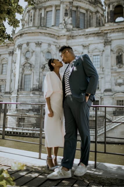 a woman in a white dress looks lovingly at a man in a gray suit