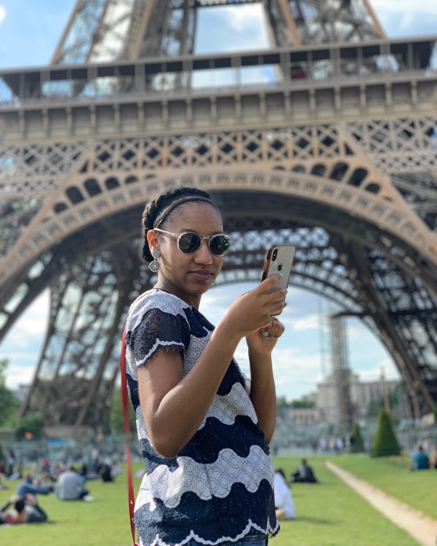 a woman taps her phone in front of a metal tower