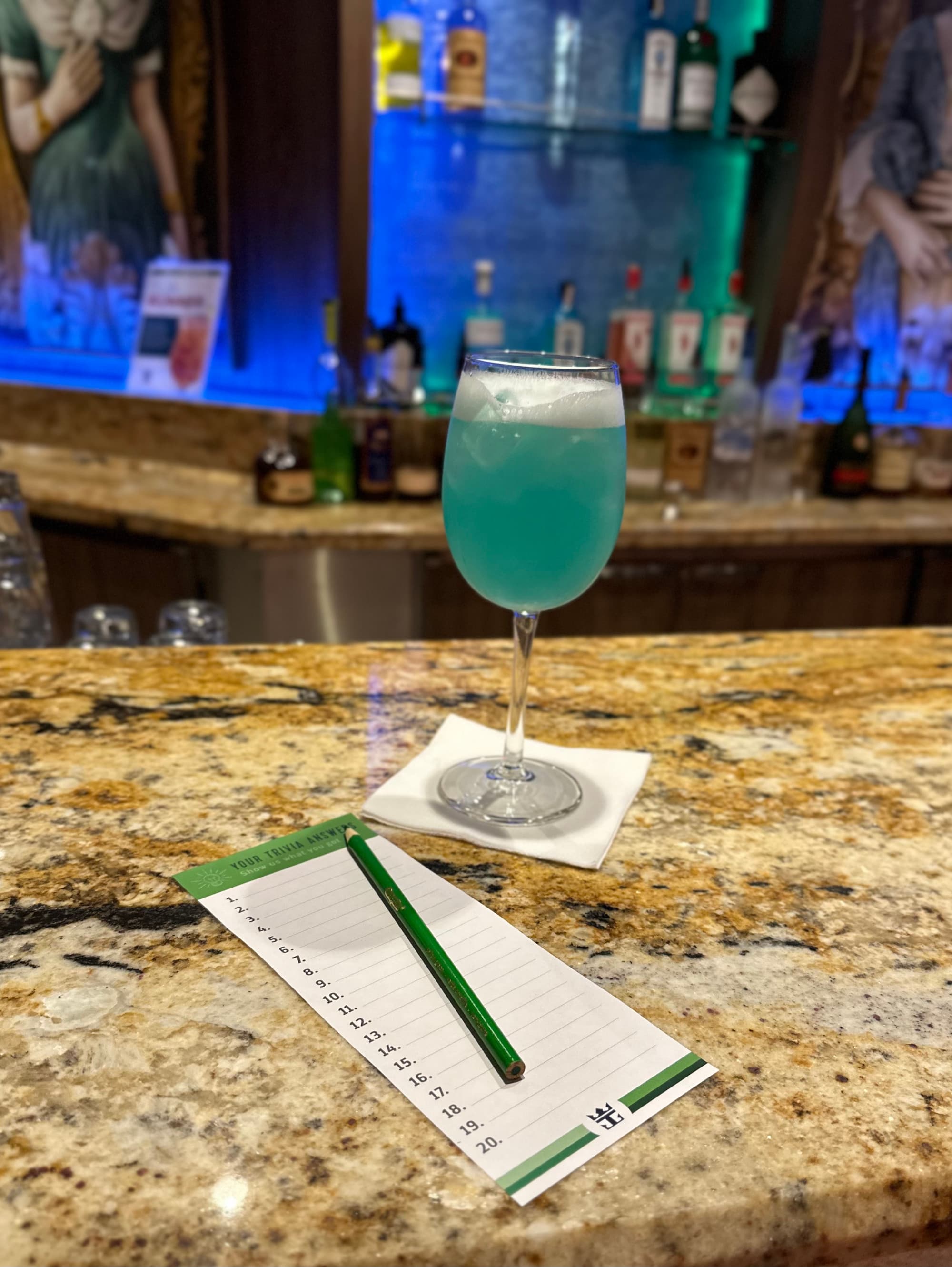 A blue drink in a wine glass at a bar