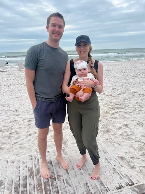 A couple posing on the beach with a baby during the daytime