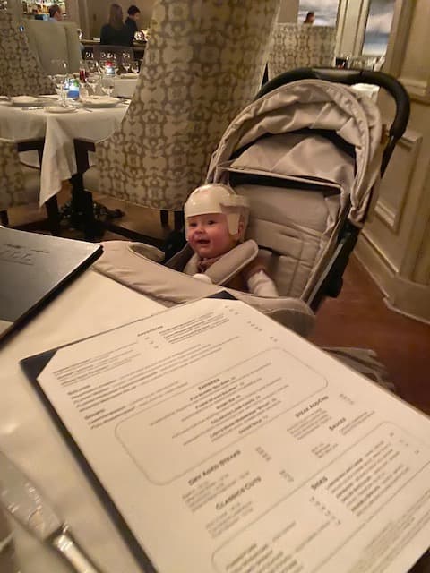 A baby sitting in a stroller at an indoor restaurant