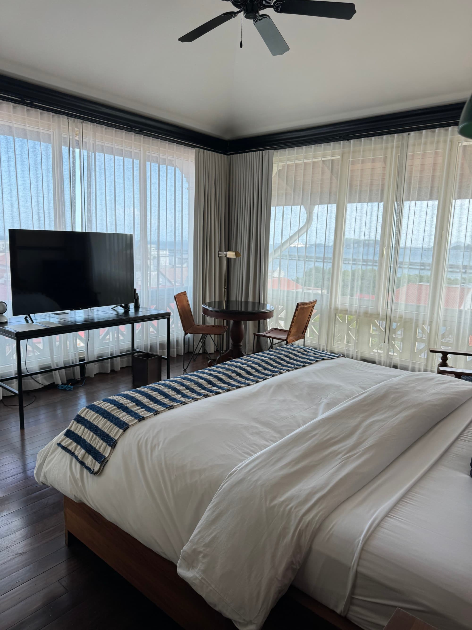 Hotel bedroom with large windows and a nice sitting area in the corner.