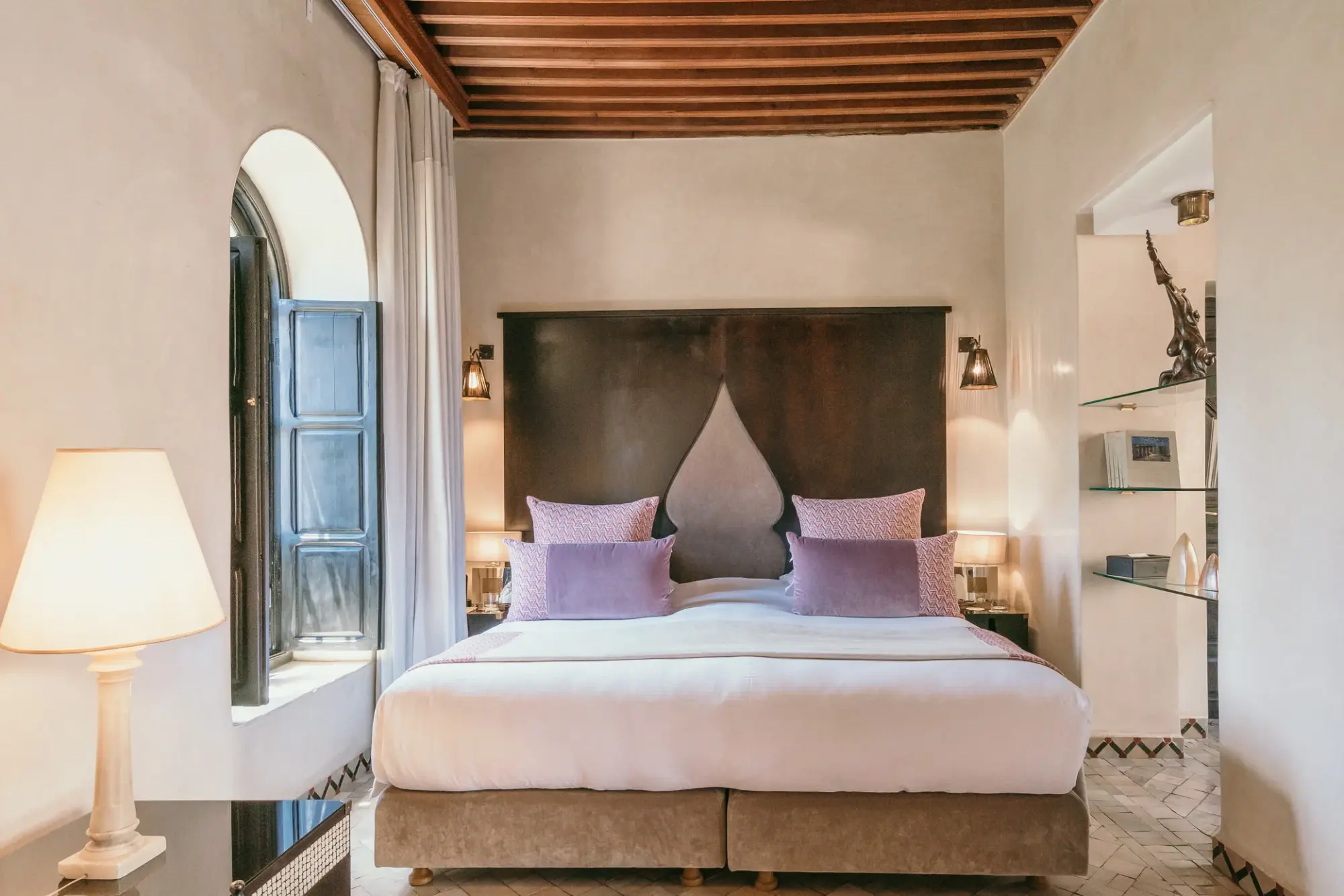 a white bed with a tall headboard and purple pillows