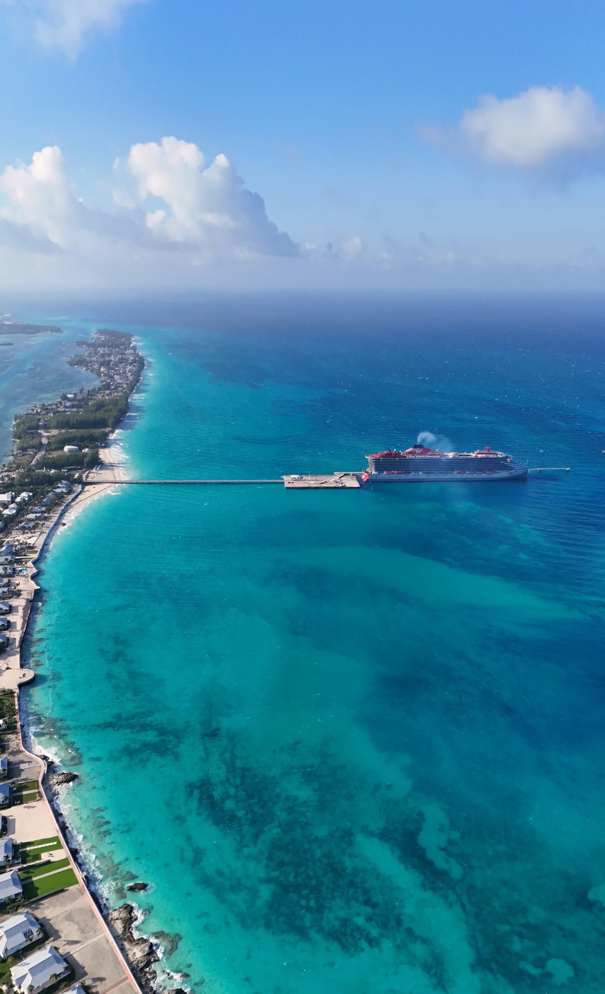 A Virgin cruise ship in port in the ocean off of a strip of land