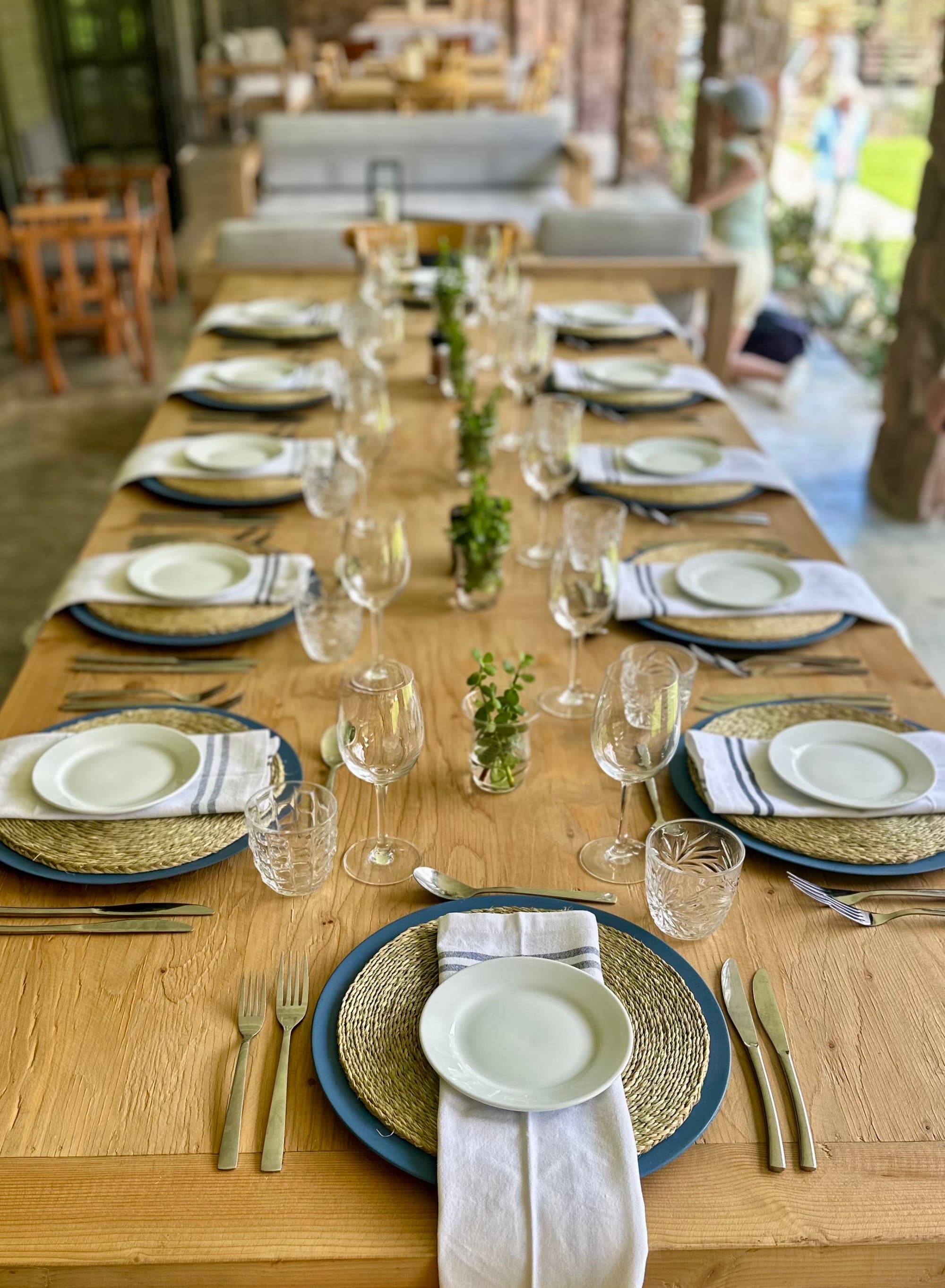 A view of a long wooden table set for multiple people with beautiful centerpieces.