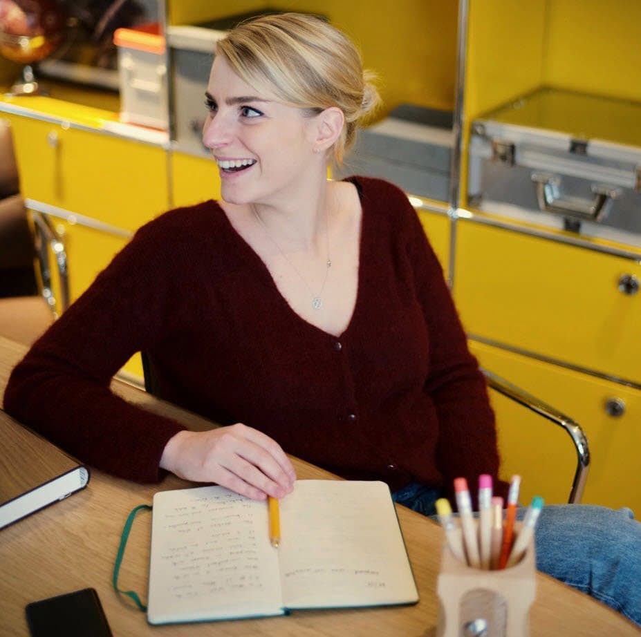 a woman in a red sweater rights in a green notebook