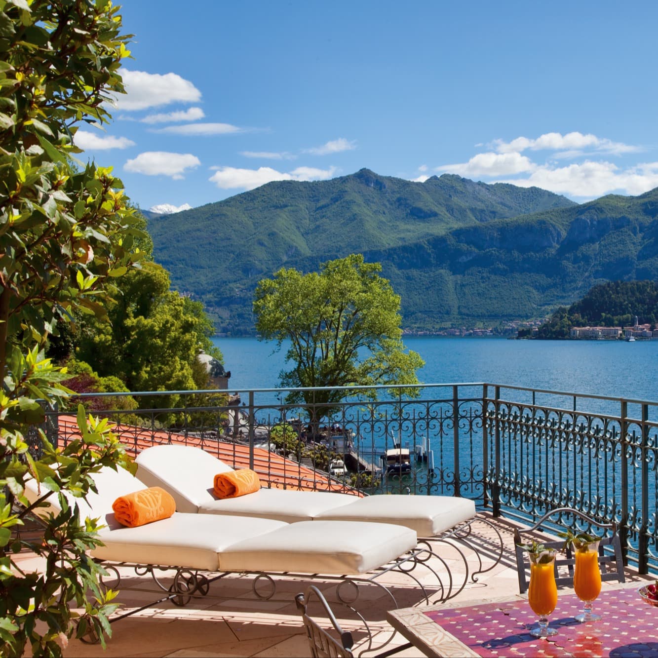 two lounge chairs on a terrace overlook a lake on a sunny day
