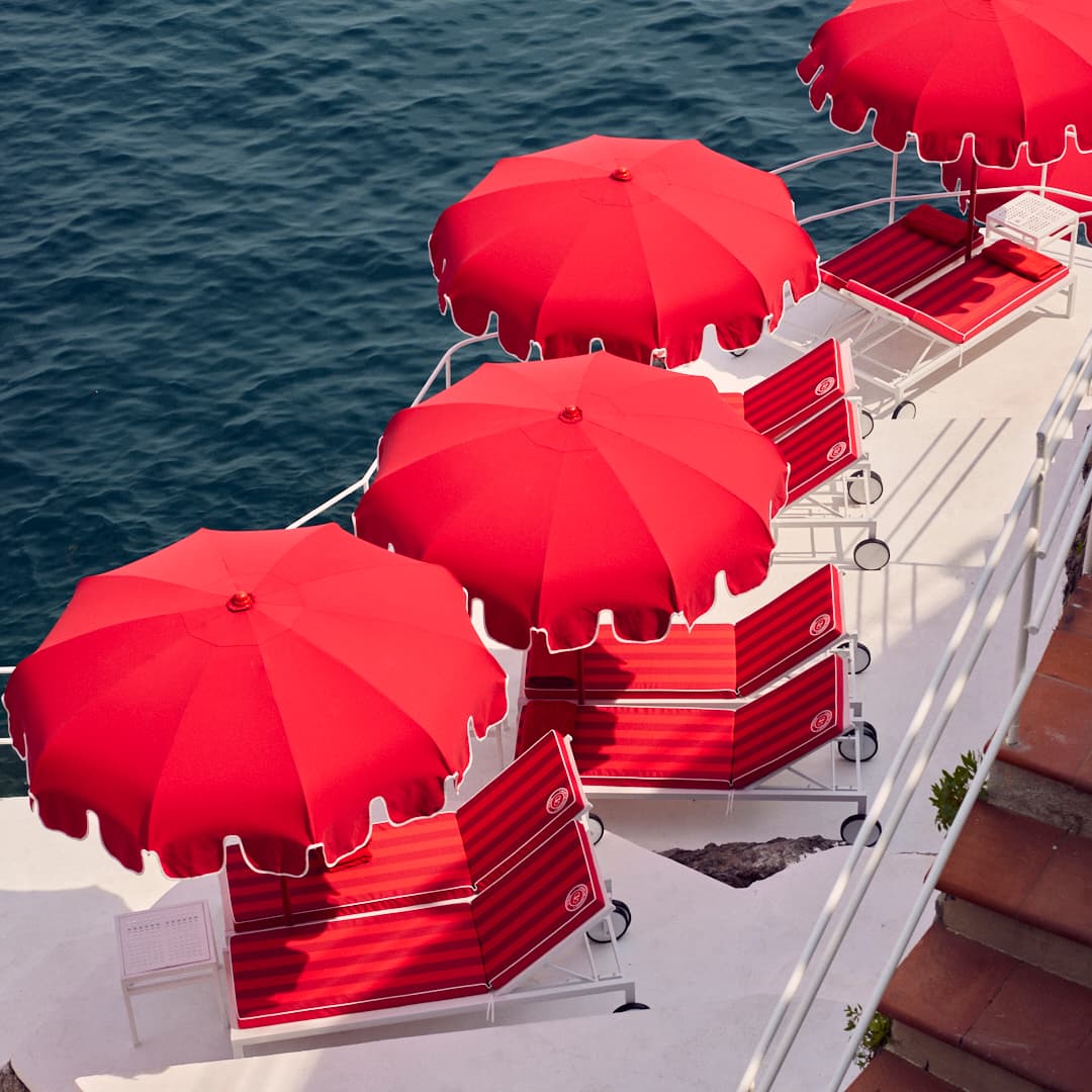 aerial view of red lounge chairs and red umbrellas overlooking the sea