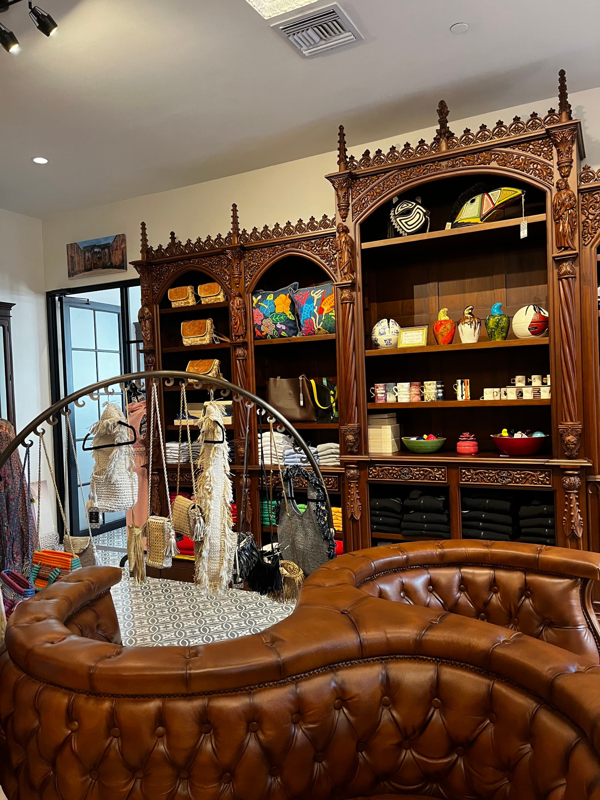 A gift shop with beautiful brown leather seating, shelves with colorful merchandise and a door in the back left corner.