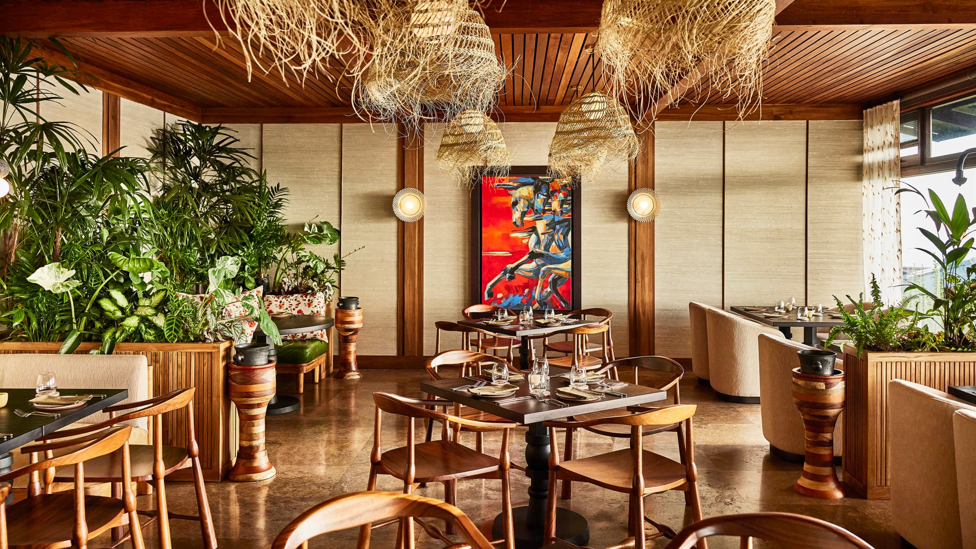 wooden tables in a sleek dining room with a red painting