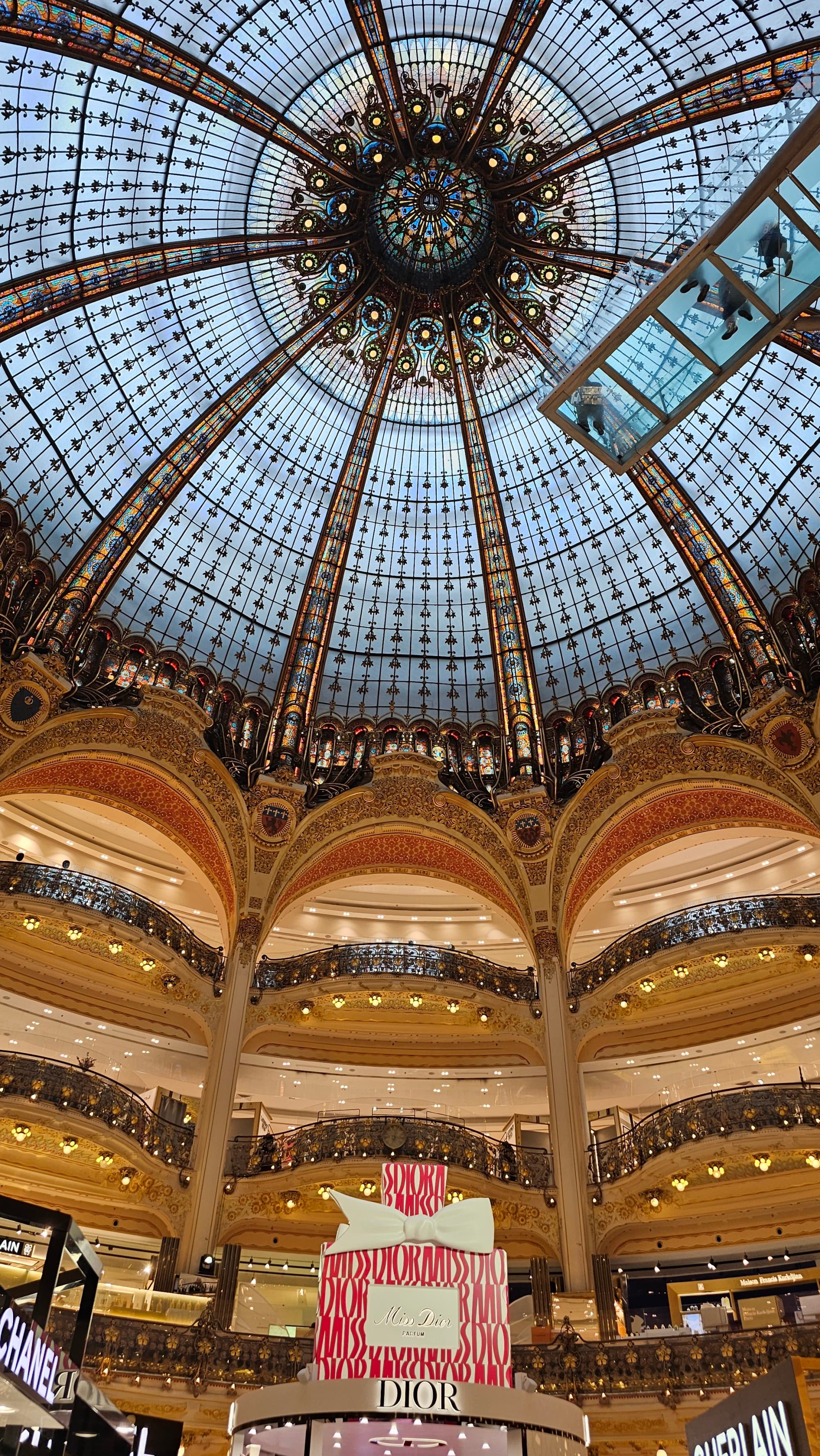 An intricate glass dome ceiling above several floors of department stores in one of the best shopping areas in Paris.