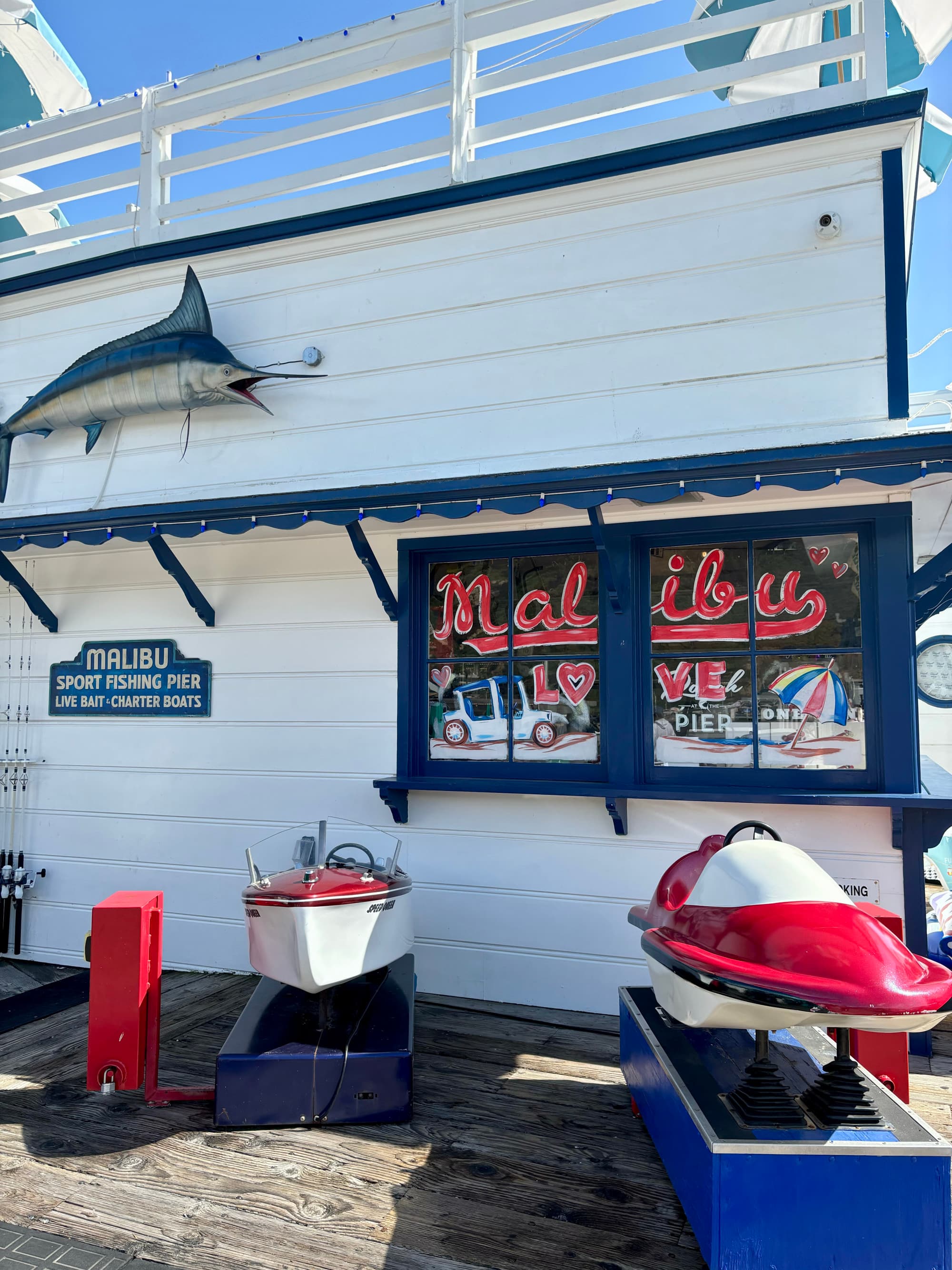 A view of a seafood shack in Malibu with a swordfish mounted onto the restaurant exterior and a blue, red and white color palette.
