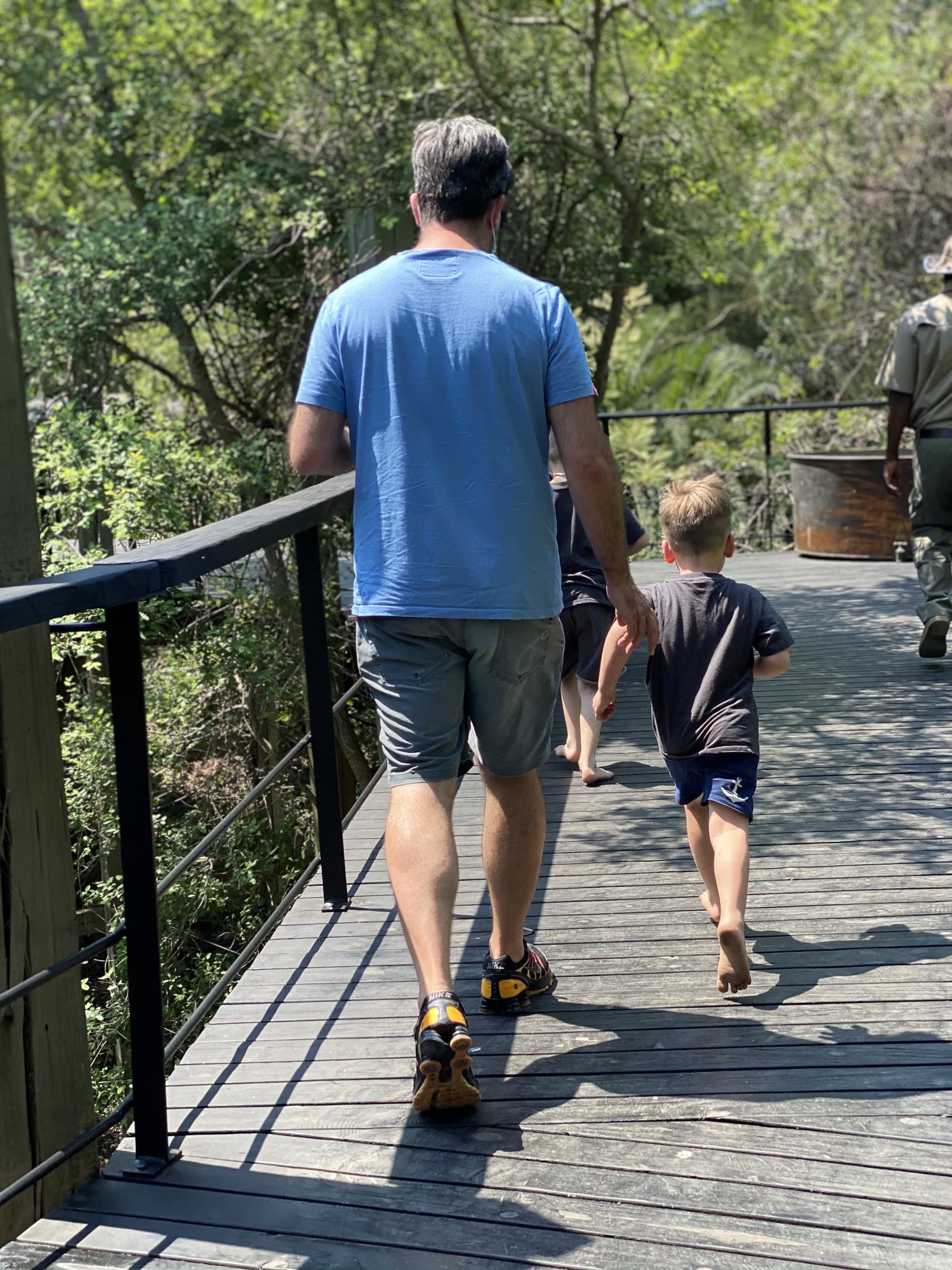 Man and child walking across a wooden deck bridge