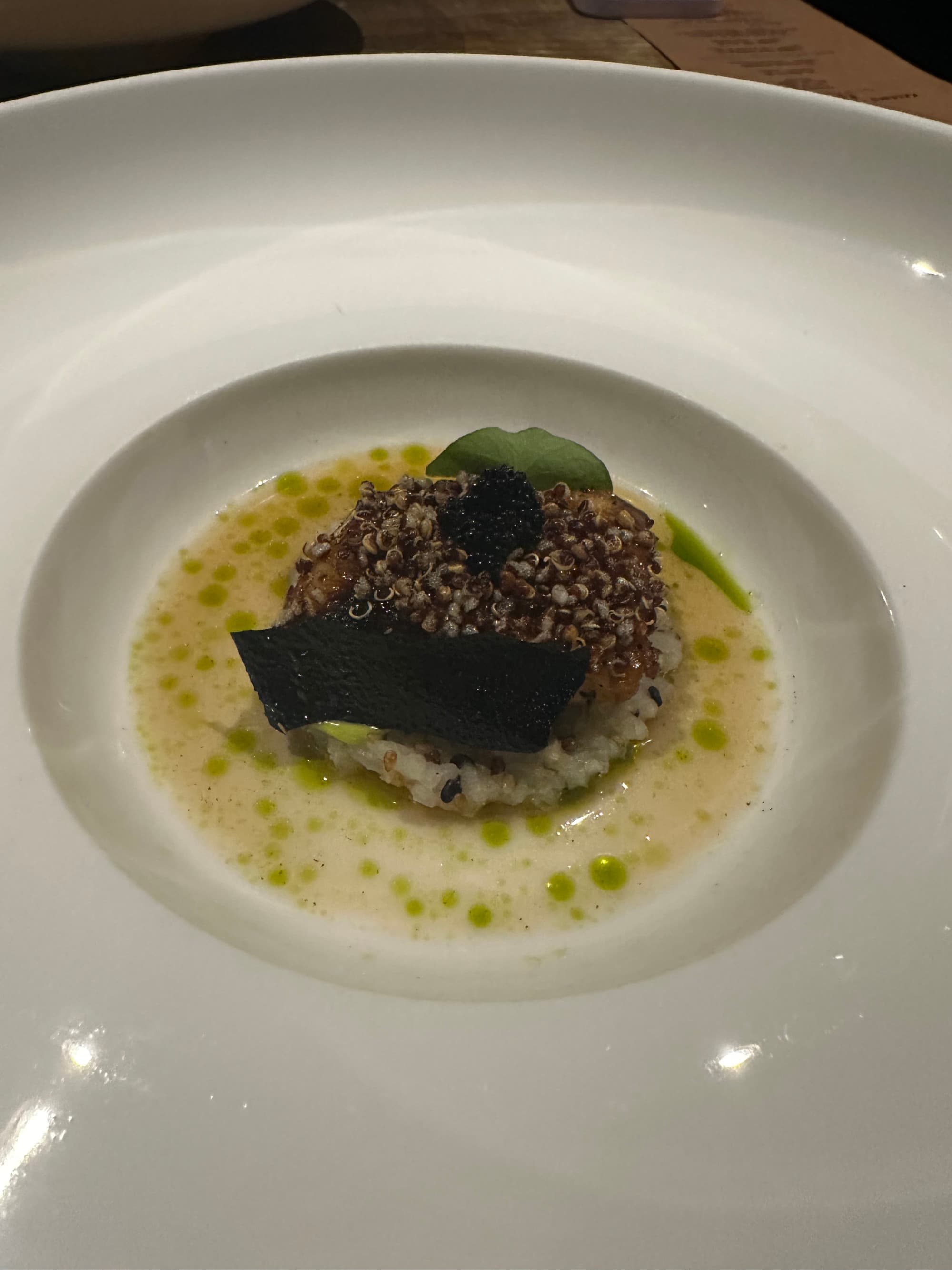 A white plate of food in a yellow and green broth.