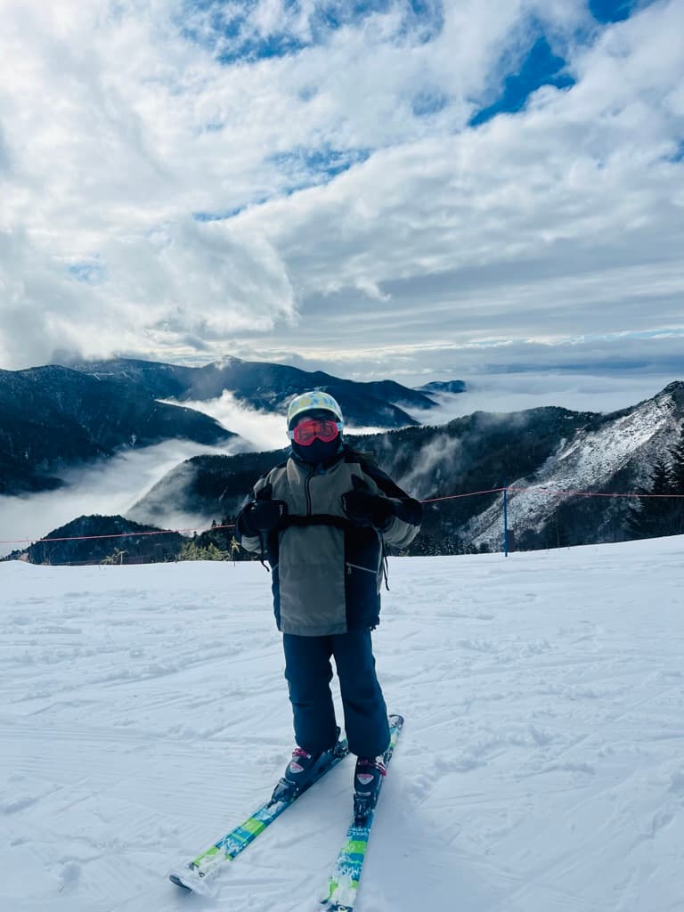 Jenna in snow gear on skis posing in front of mountains in December in Japan.
