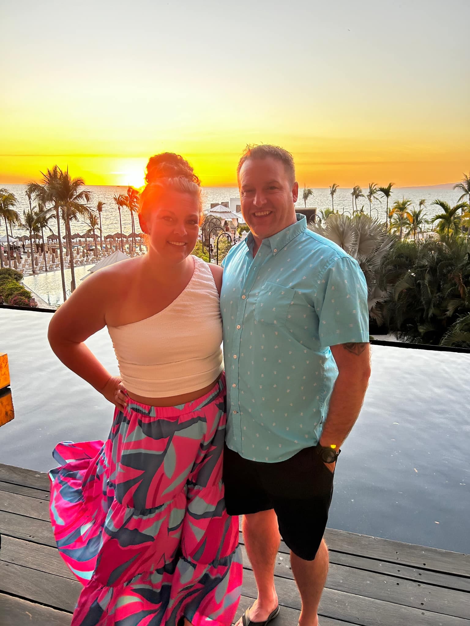 Two people posing for a photo at sunset