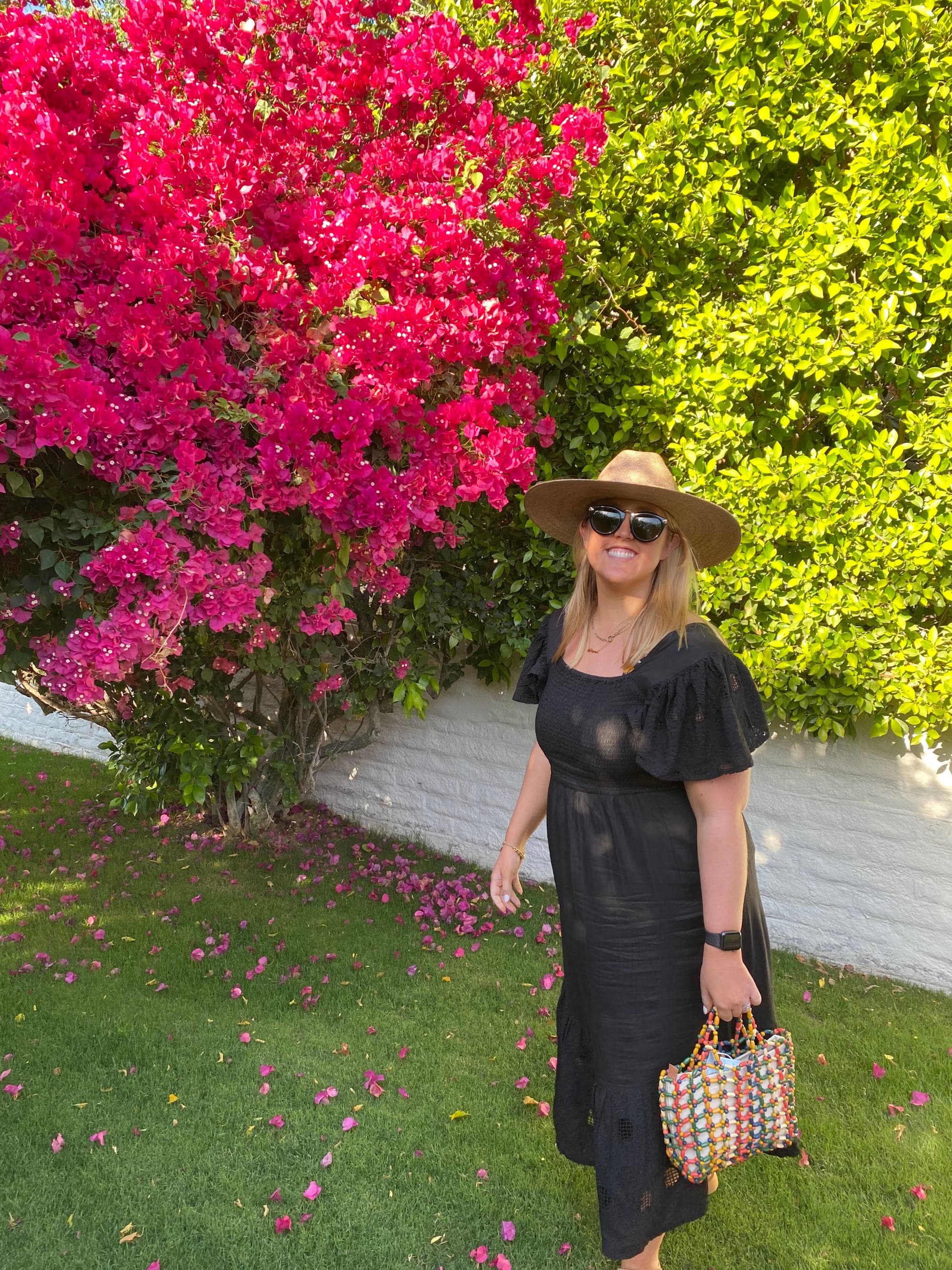 Travel advisor posing with lovely foliage and flowers in the distance on a sunny day