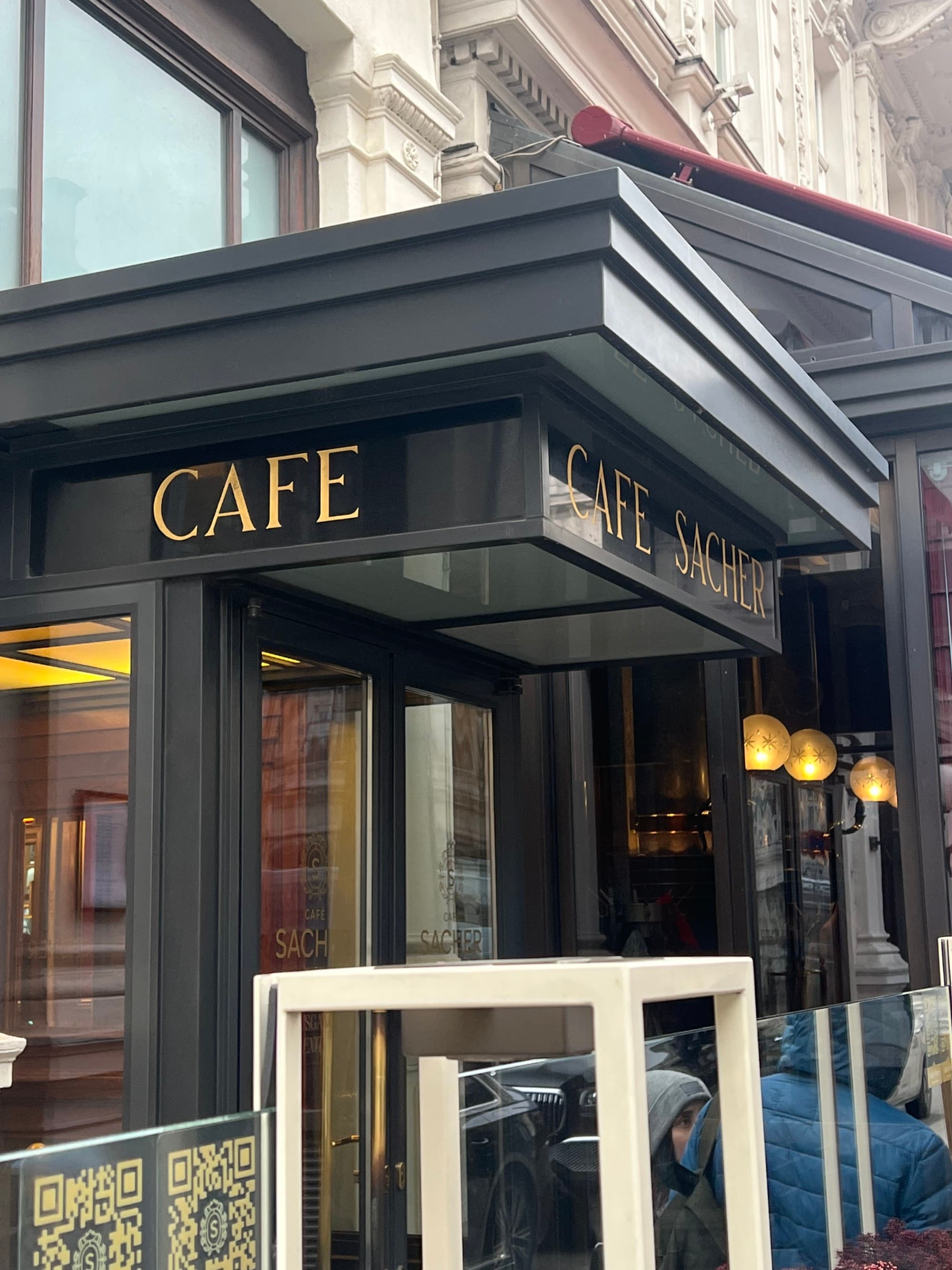 The exterior of Café Sacher Vienna Sacher Tort, a black-painted building with gold lettering