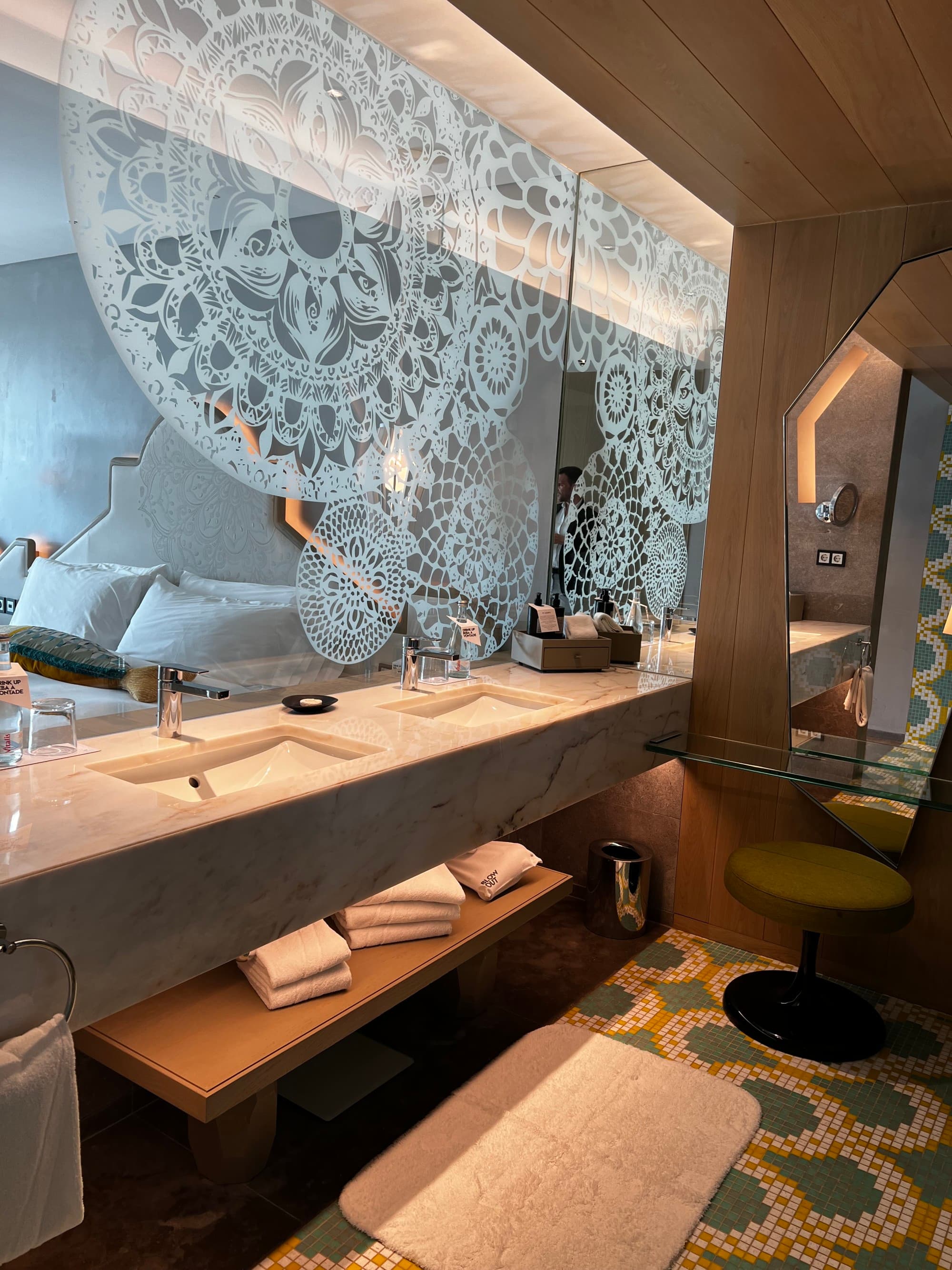 The powder room inside a guest room, with a long marble counter, sinks, and blue-and-white tiled floor