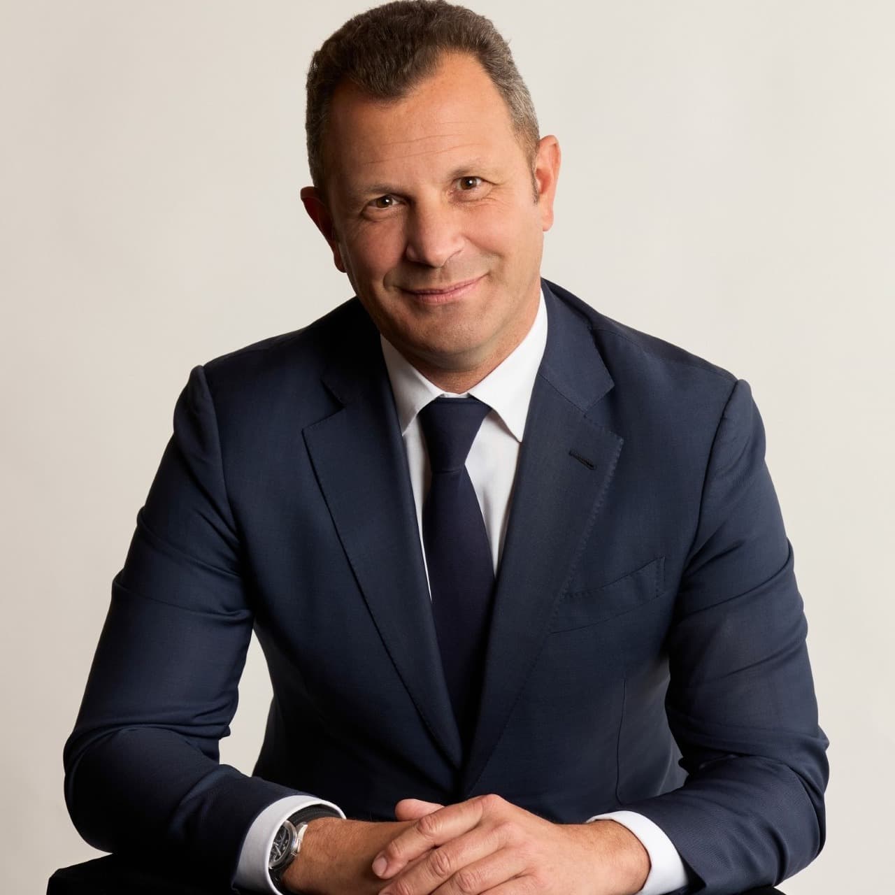 a man in a suit poses and smiles