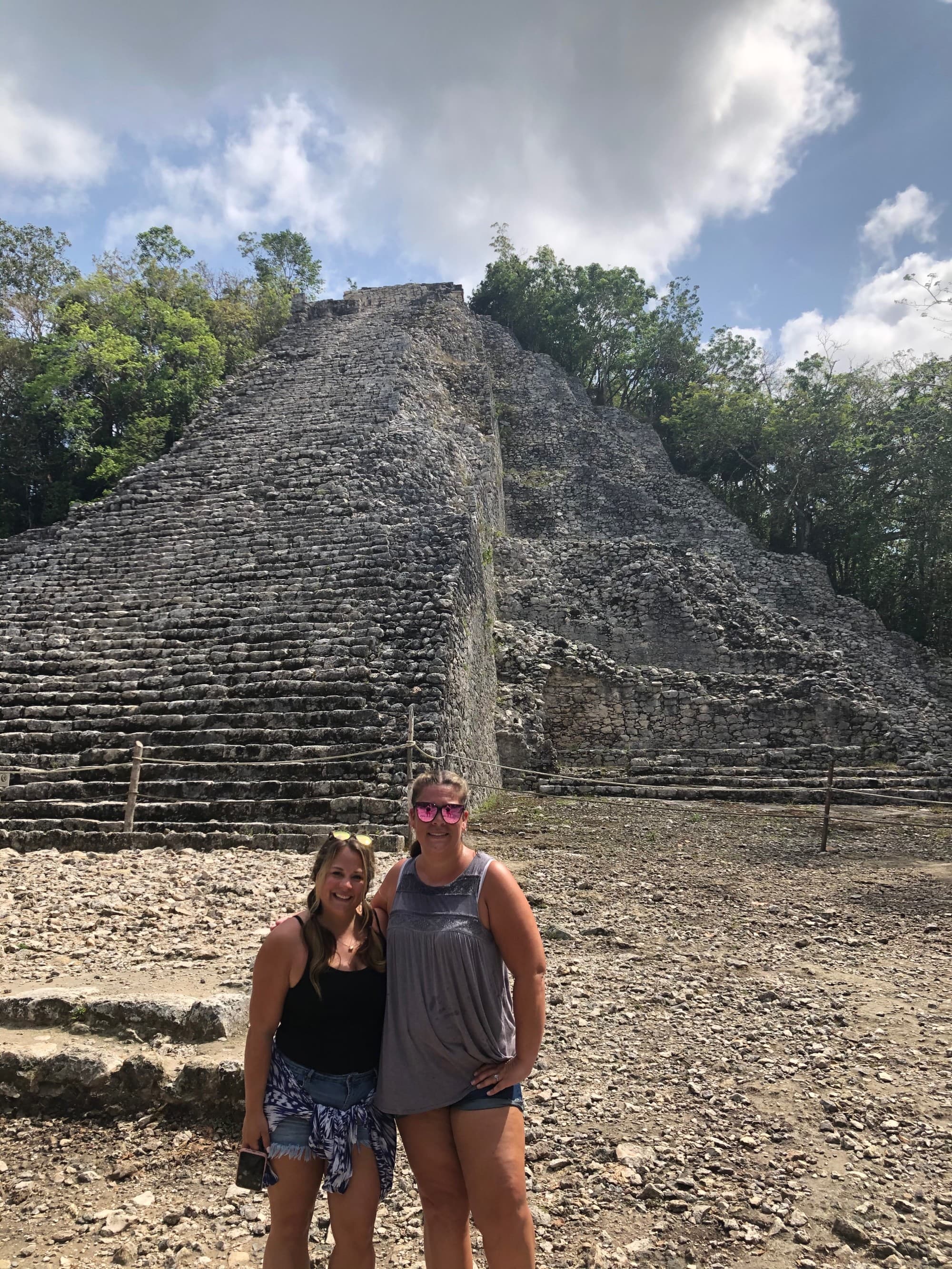 Couple posing in front of an ancient pyramid structure during the daytime