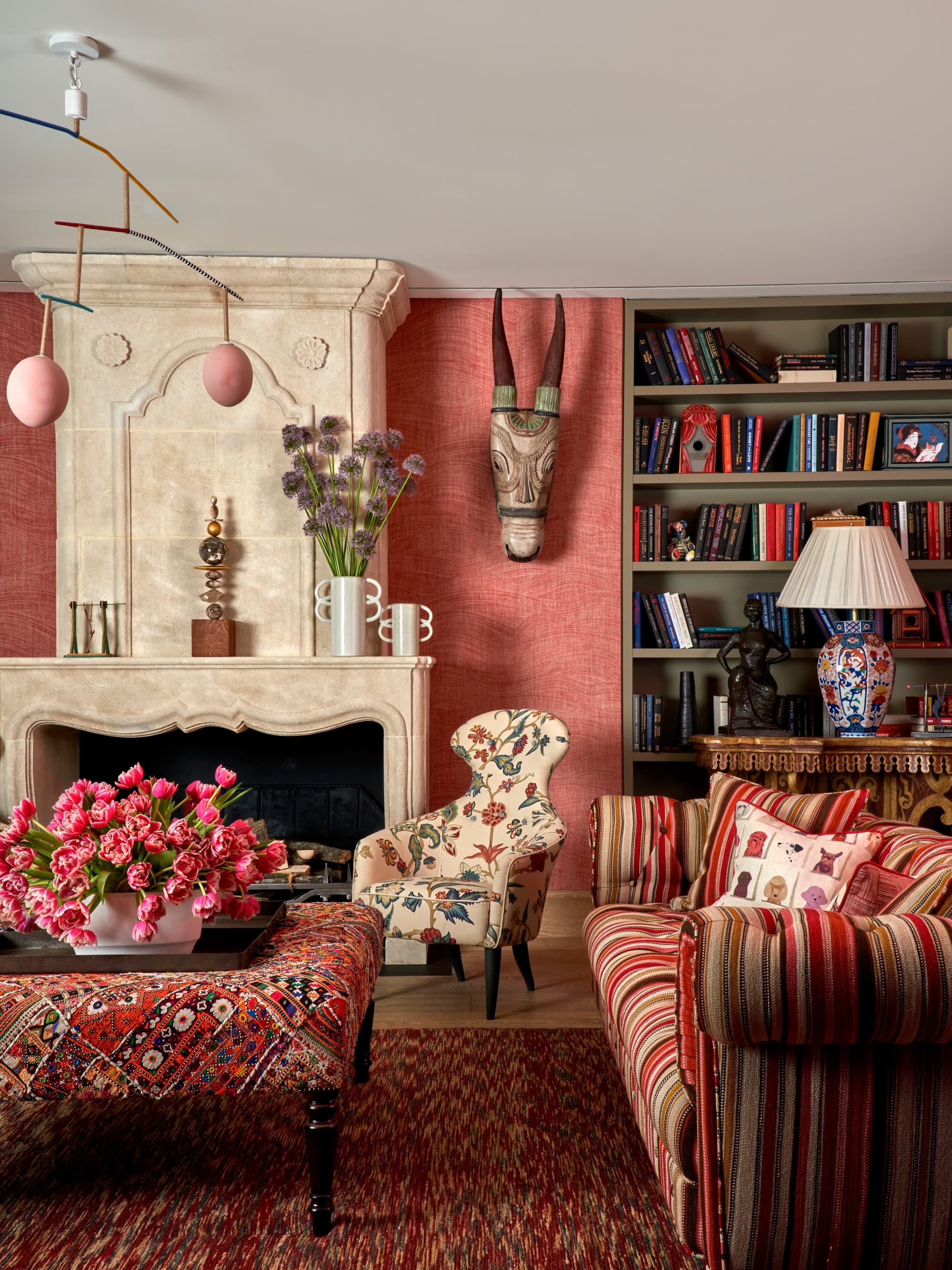 a luxe living room with brightly patterned upholstered furniture, a fireplace, and animal-head sculptures hanging on the wall