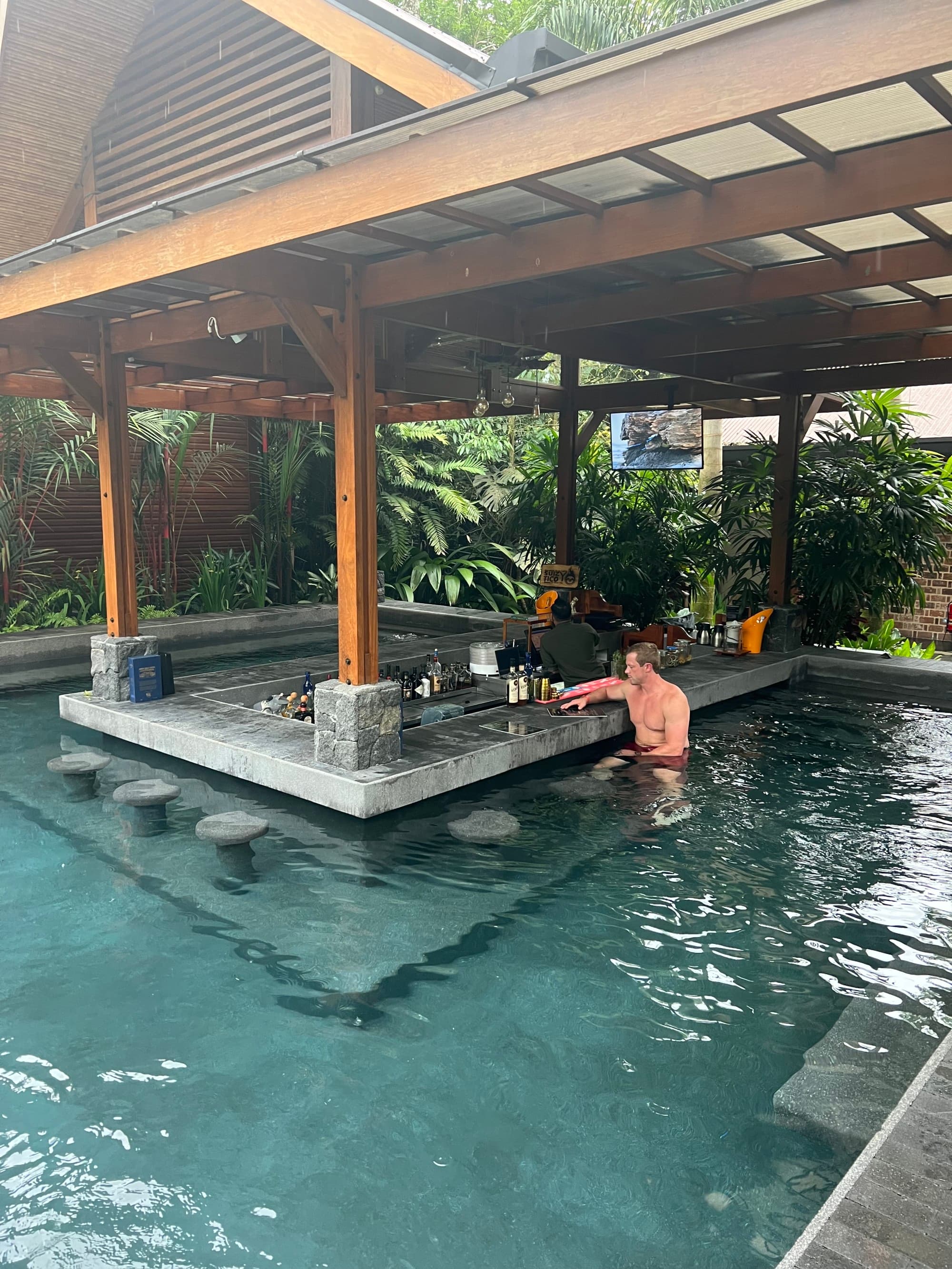 A view of a male tourist sitting at the swim up bar, enjoying a refreshing drink at the resort.