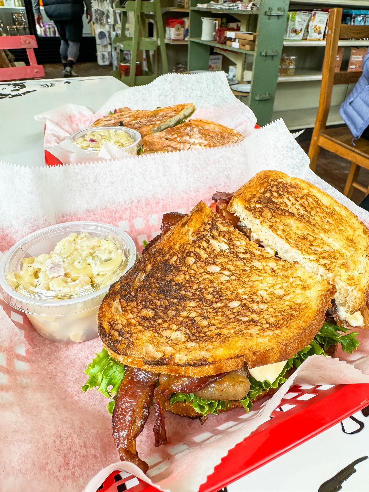 A close-up shot of two toasted sandwiches in baskets, with a side of macaroni salad at a local market.