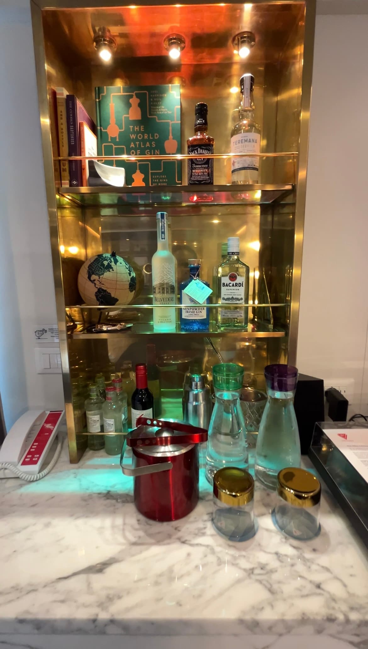 A small bar in the wall holding bottles of liquor
