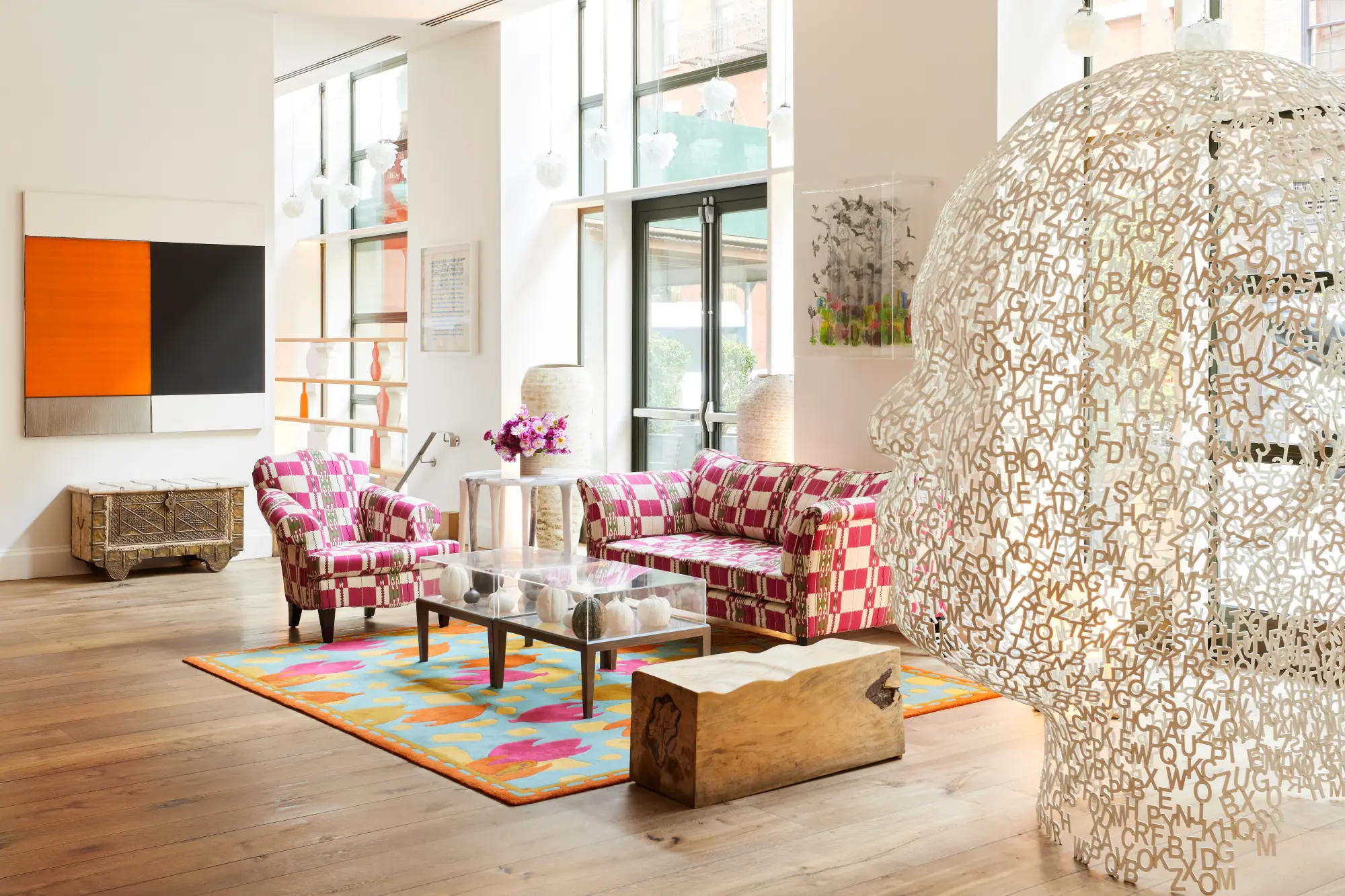 a large sculpture of a head in an art-filled lobby with pink couches
