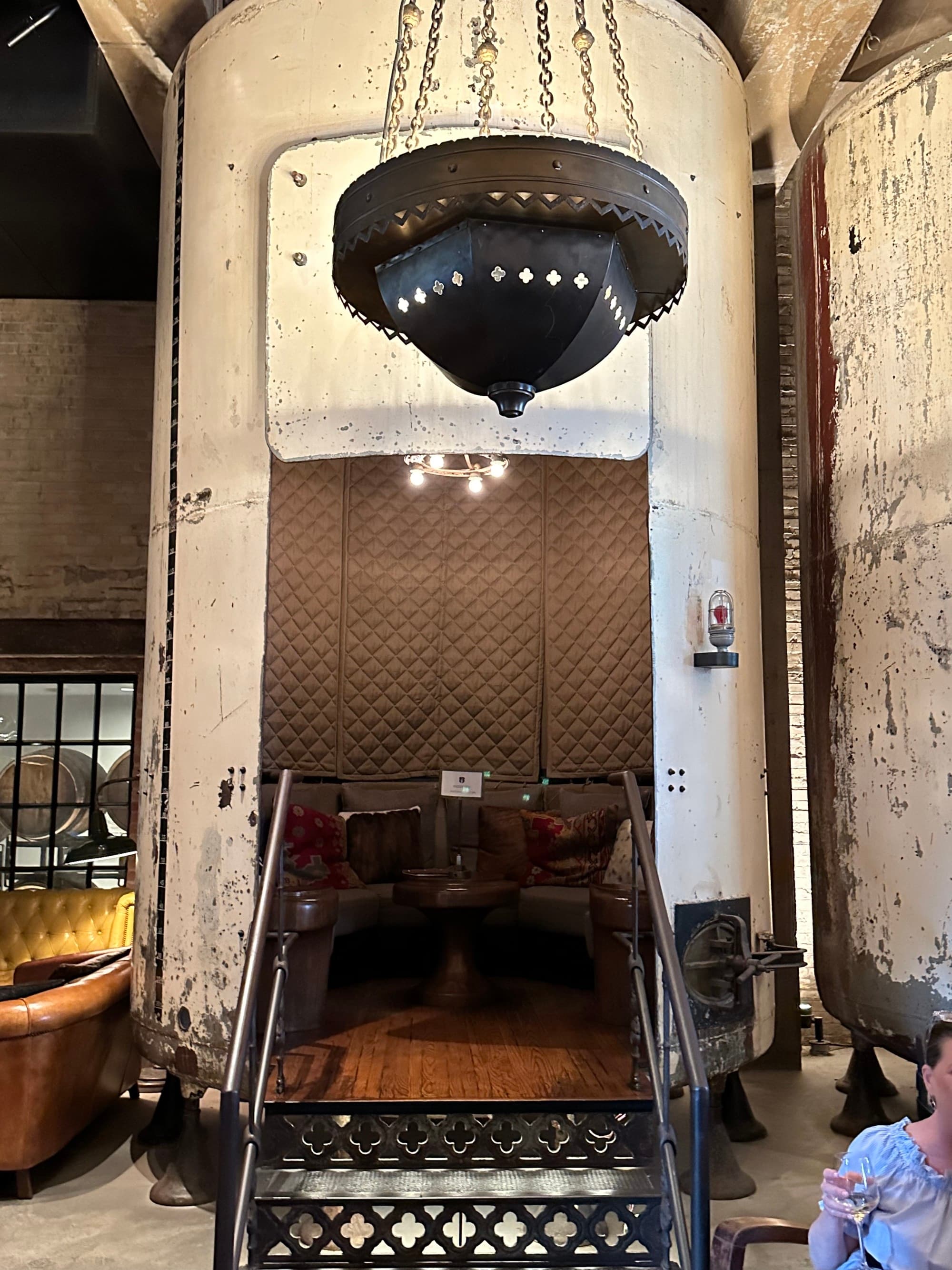 An old-fashioned, metal brewery tank made into a small seating area with a small staircase leading inside of it.
