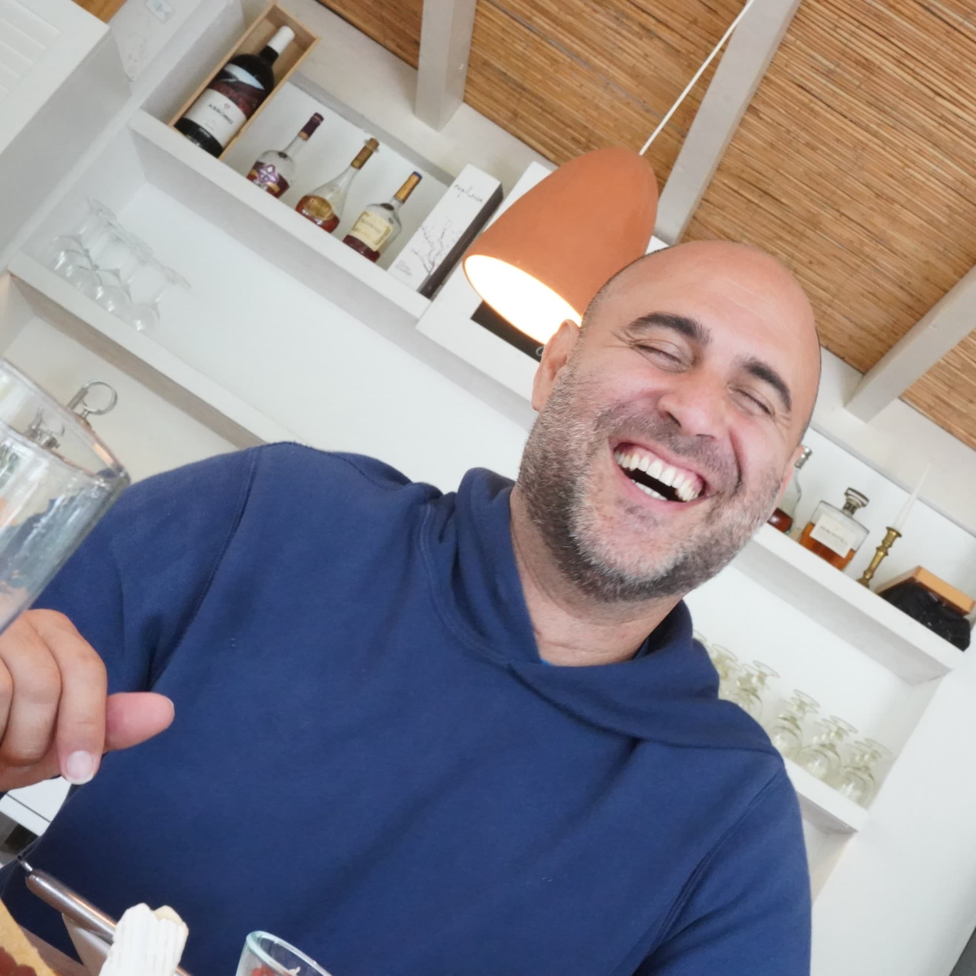 a man in a blue shirt laughs in a kitchen