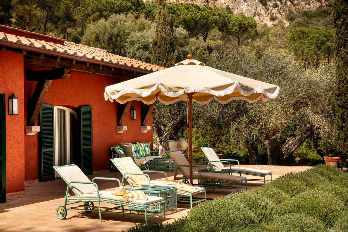 loungers beneath an umbrella near a red villa